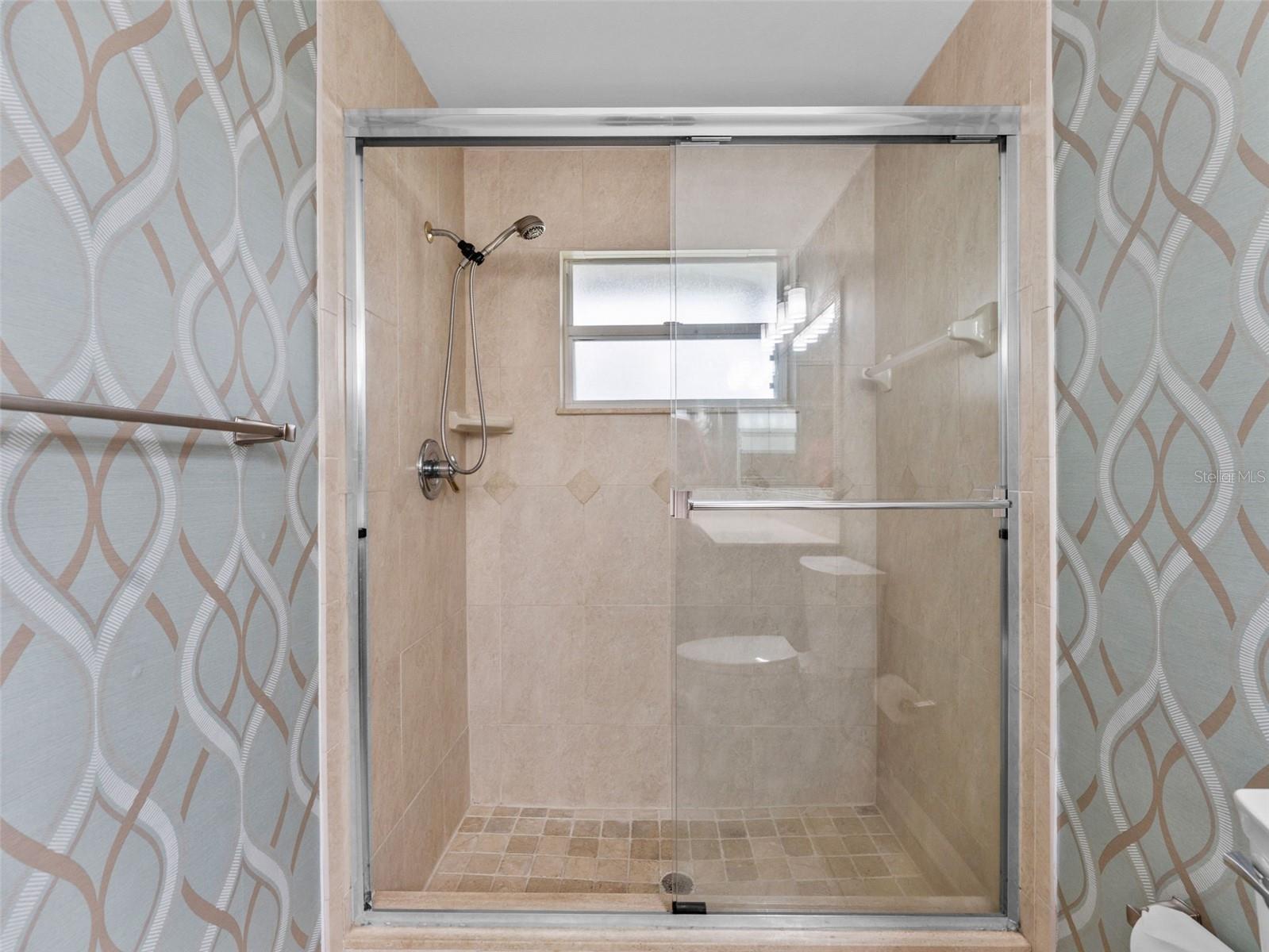 Primary ensuite bathroom featuring a spacious, stylish glass shower