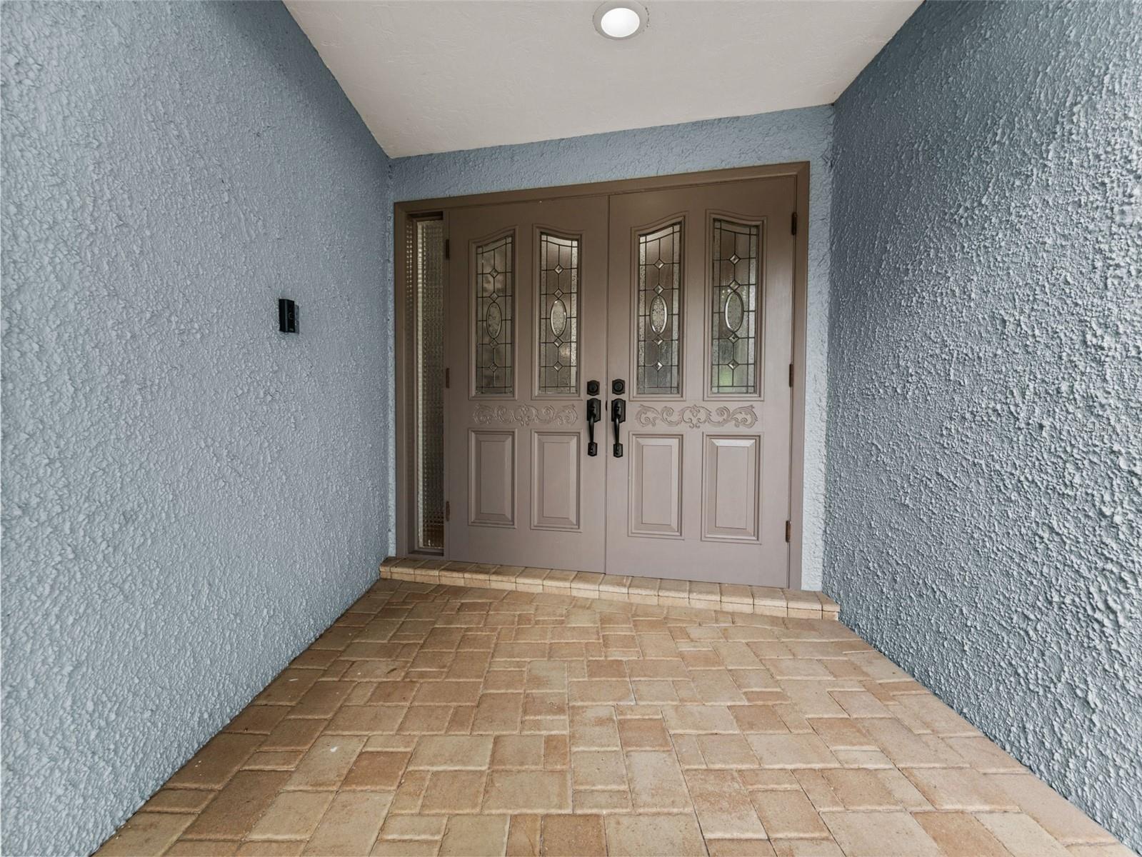 The paver walkway and elegant double door entry provide a warm and stylish welcome