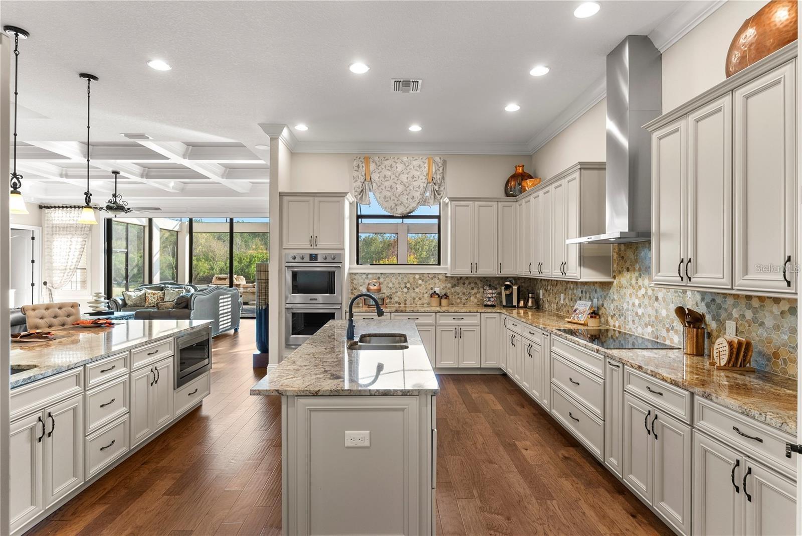 The gourmet kitchen is a chef’s dream, offering a double island layout, double ovens, a digital cooktop with hood, a walk-in pantry, and an oversized custom refrigerator, perfect for entertaining.