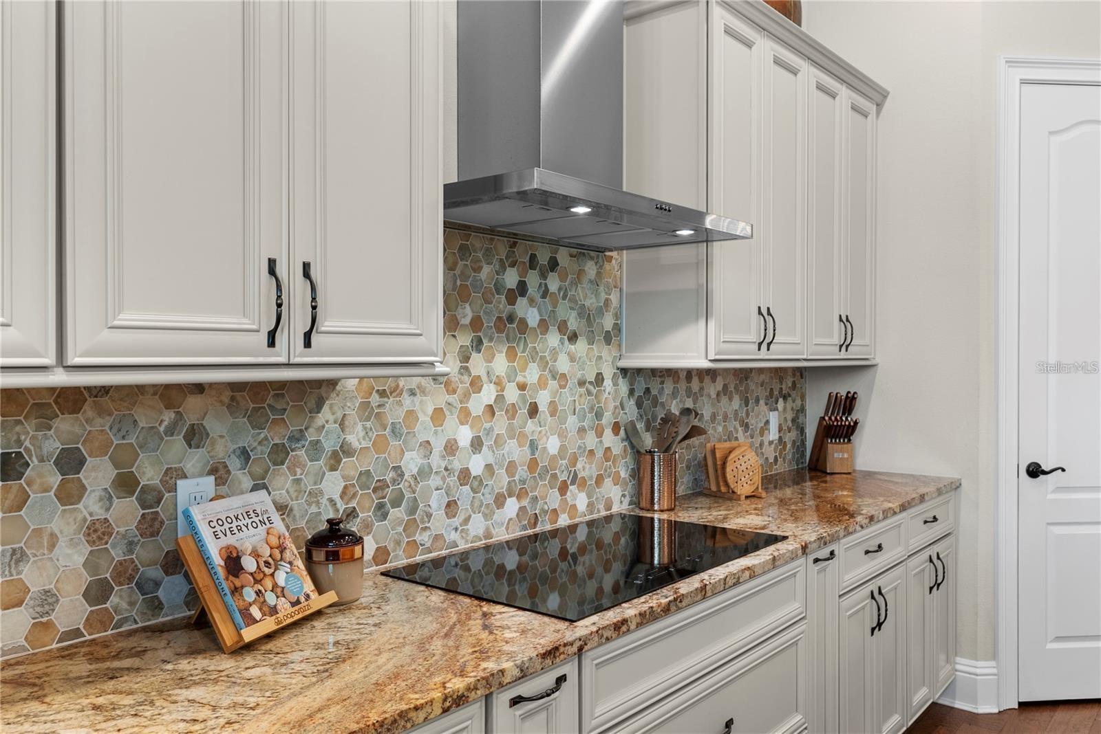 The kitchen features a convection oven and a sleek cooktop with a designer range hood, combining style and efficiency for a superior culinary experience.