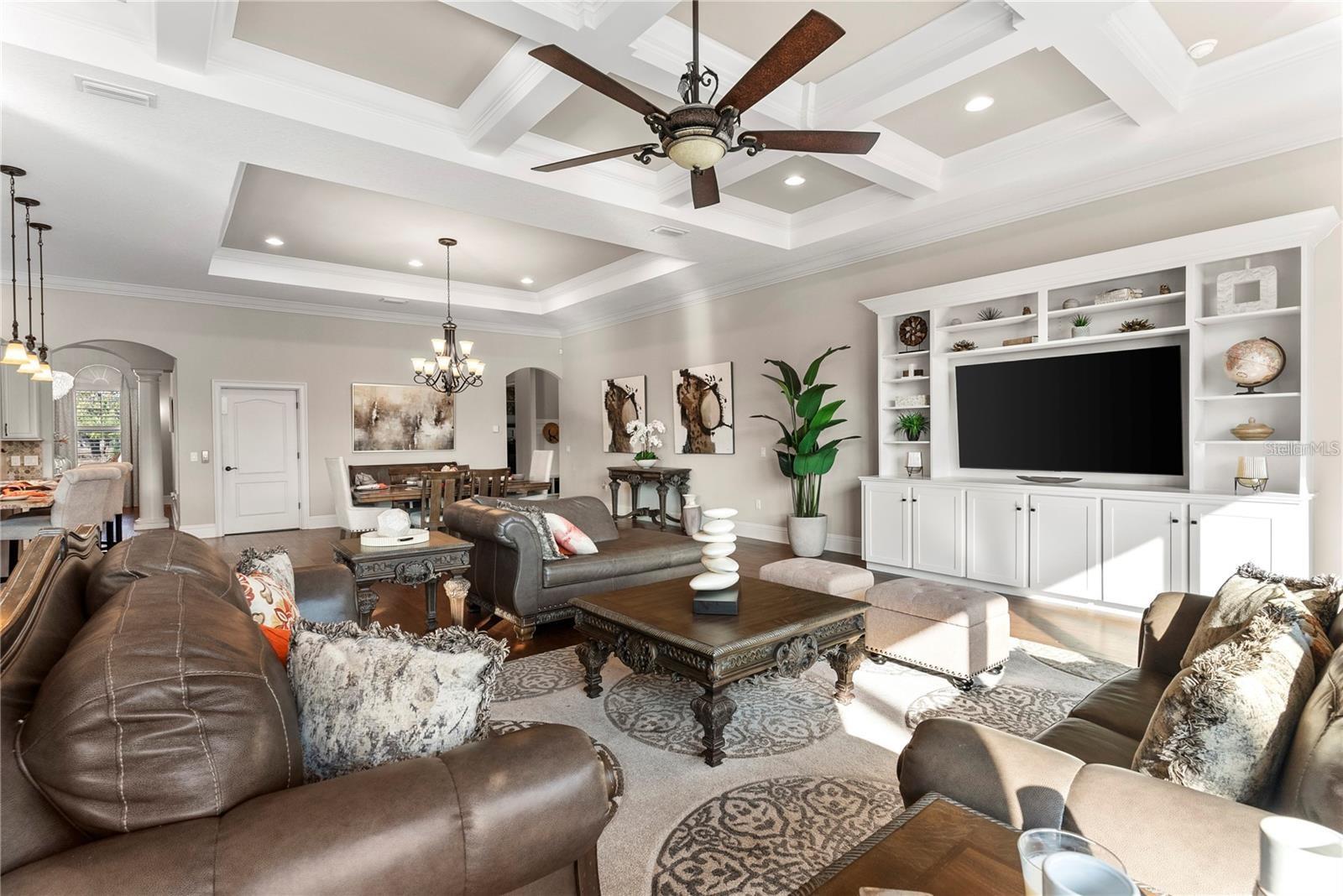 The highlighted built-in entertainment center, coffered ceilings, recessed can lights, and intricate tray ceilings for a sophisticated touch.