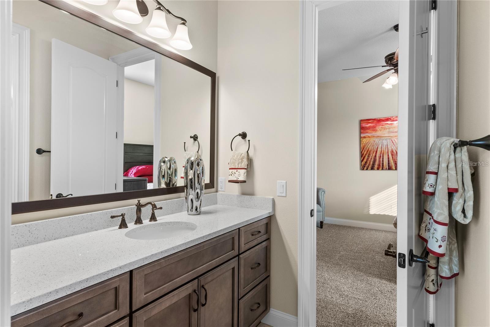 This passthrough bathroom offers a thoughtfully designed layout, featuring the ability to close off the water closet and the shower-tub combination, allowing one person to dress in privacy while another enjoys a shower.