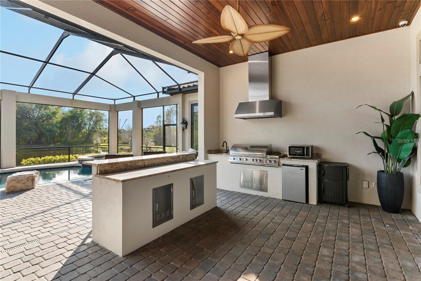 The outdoor kitchen offers a beautiful bar and range hood.