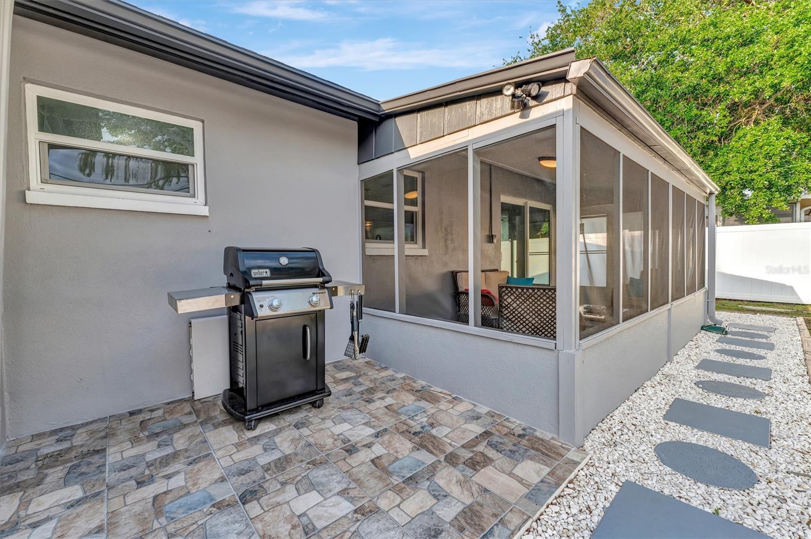 Paver deck located off screened in patio with weber grill