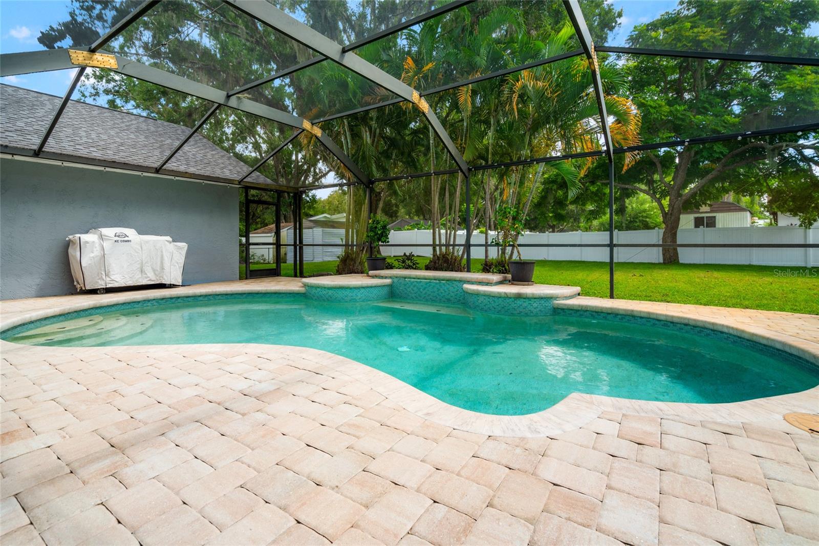 Pool and paver deck looking out at backyard