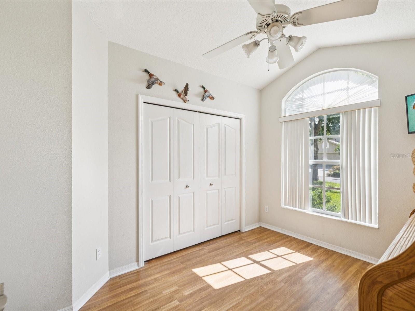 This east facing bedroom features a spacious closet and laminate floors with a ceiling fan.