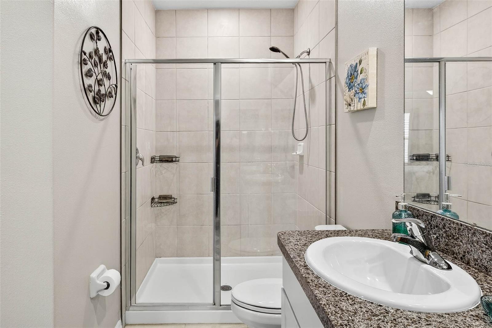 Shower tiled with glass front doors.