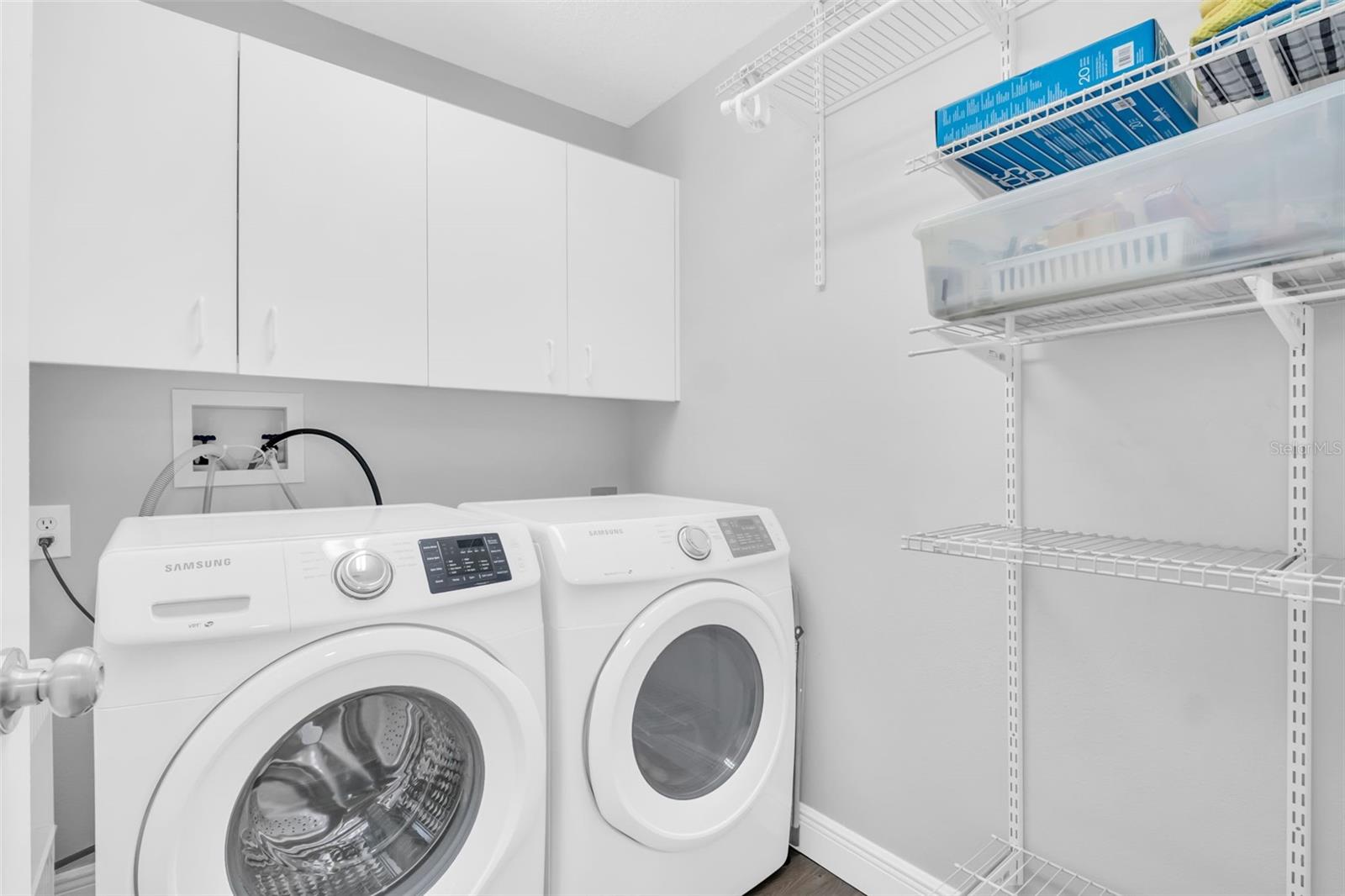 Large indoor laundry with additional cabinets and shelving for storage~