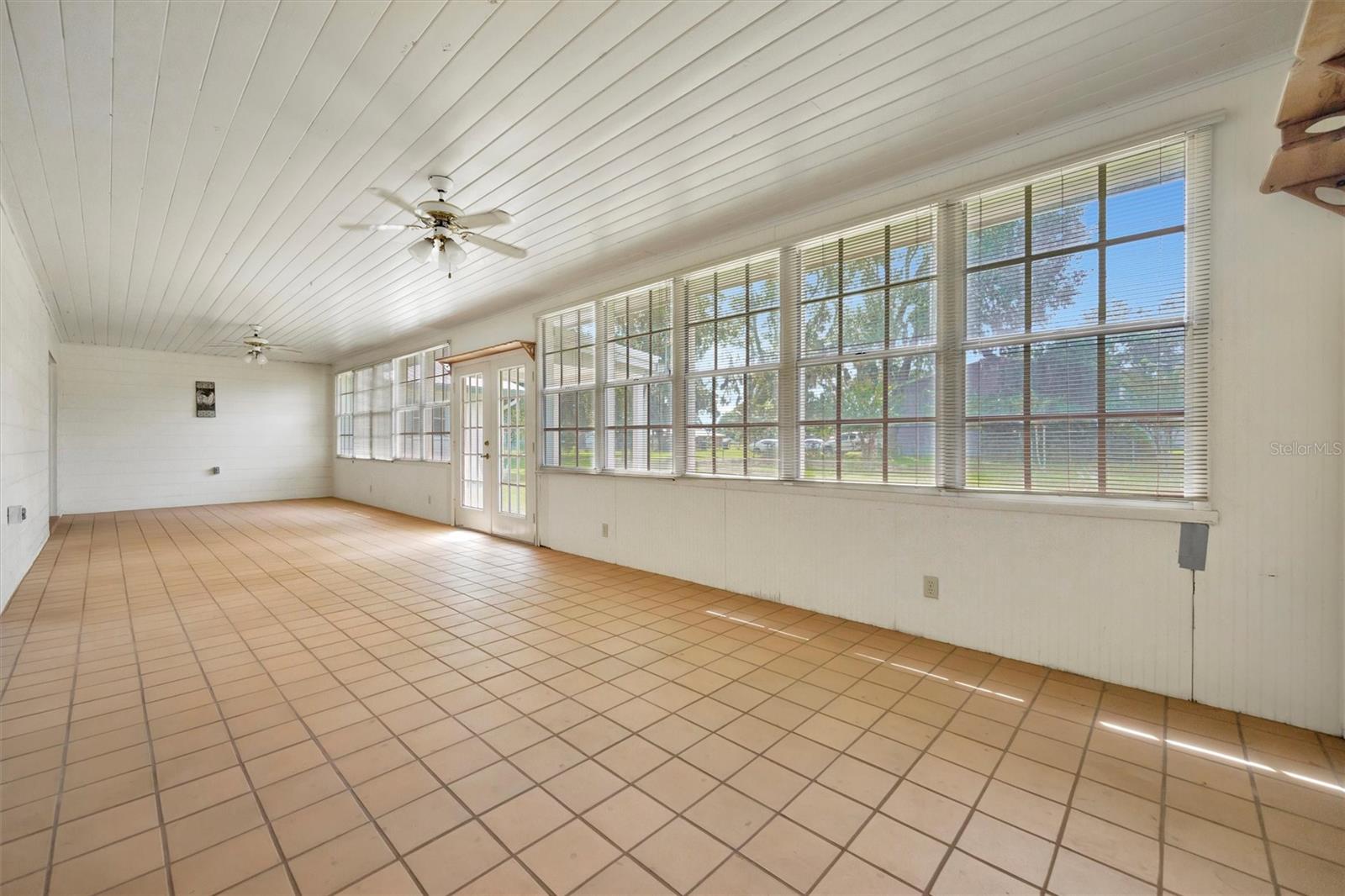 Spacious sunroom filled with natural light from large windows.