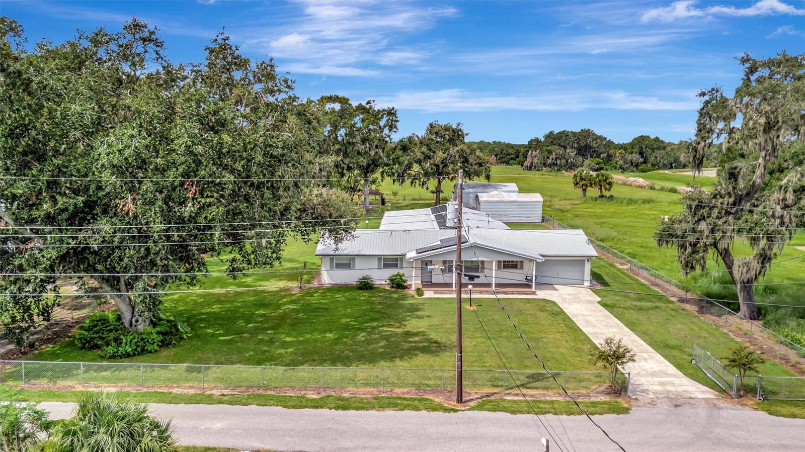 Gated property with a long private driveway, surrounded by mature trees and lush greenery.