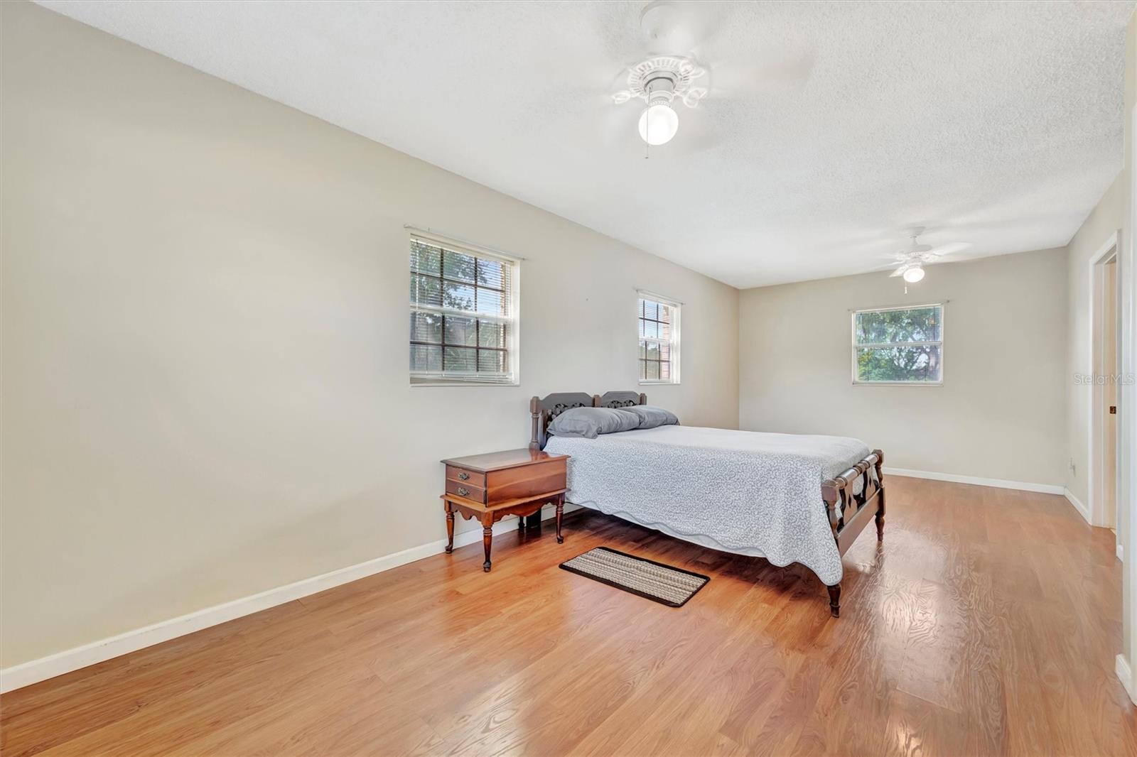 Spacious master bedroom with wood-look flooring and great natural light.