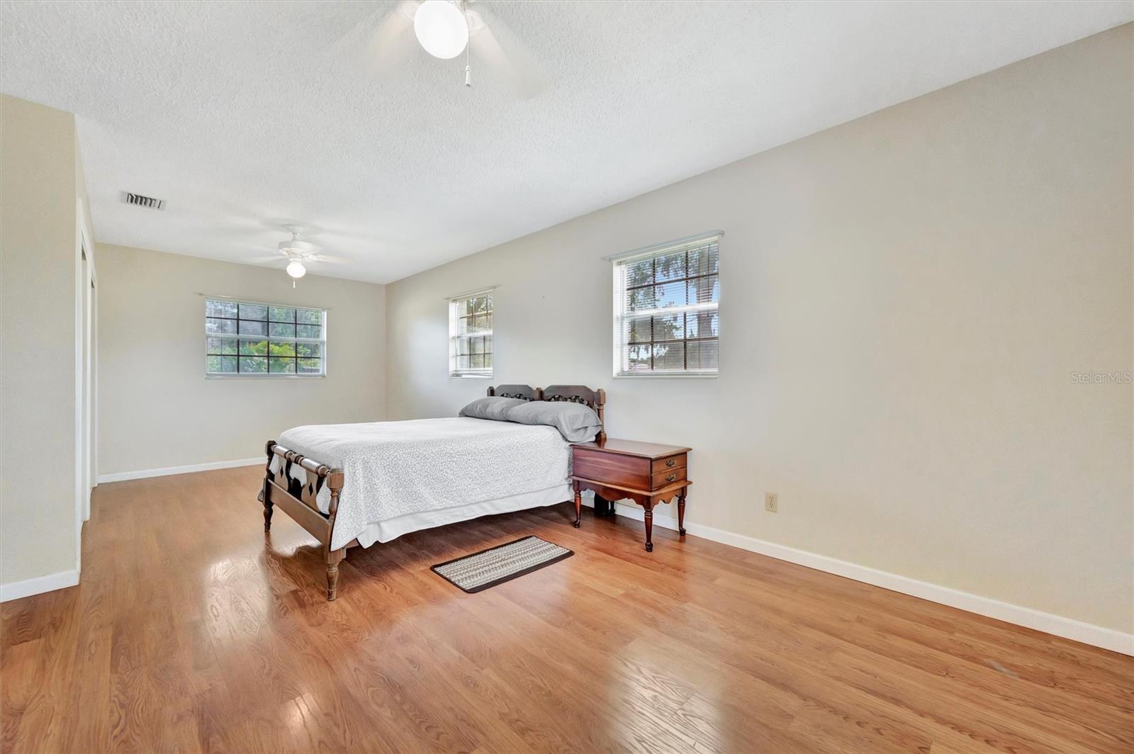 Multiple windows and ceiling fans enhance comfort in this airy primary suite.