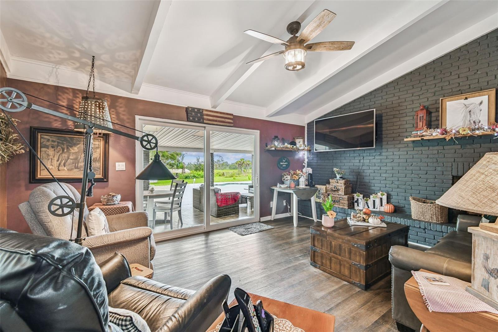 Family Room with Vaulted Ceiling beams and wood burning fireplace.  Sliders to the lanai and pool area.