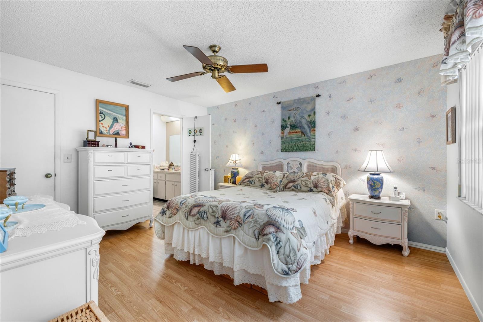 The primary bedroom features laminate flooring, ceiling fan, walk-in closet and adjacent en-suite bathroom.