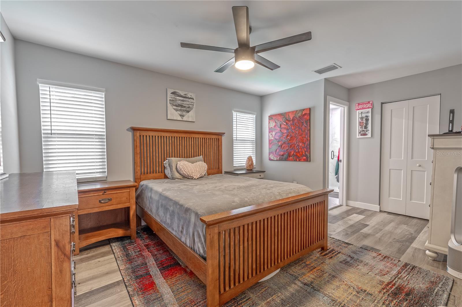 Spacious bedroom with vinyl flooring, ceiling fan/light combo, and natural light creating a relaxing retreat.