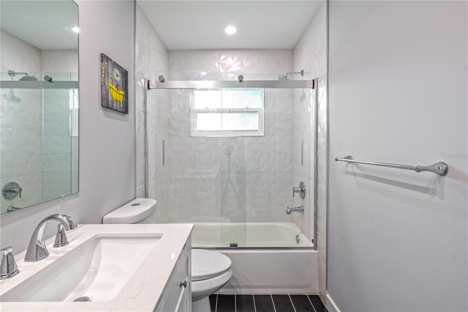Full guest bath with tub and shower combination, large-format white tile surround, recessed lighting, and ceiling exhaust fan.
