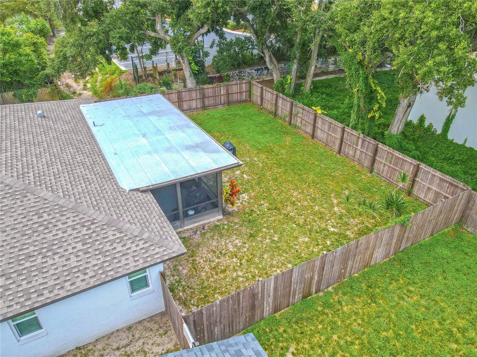 Fully fenced backyard with mature trees and open green space, providing privacy and room to play.
