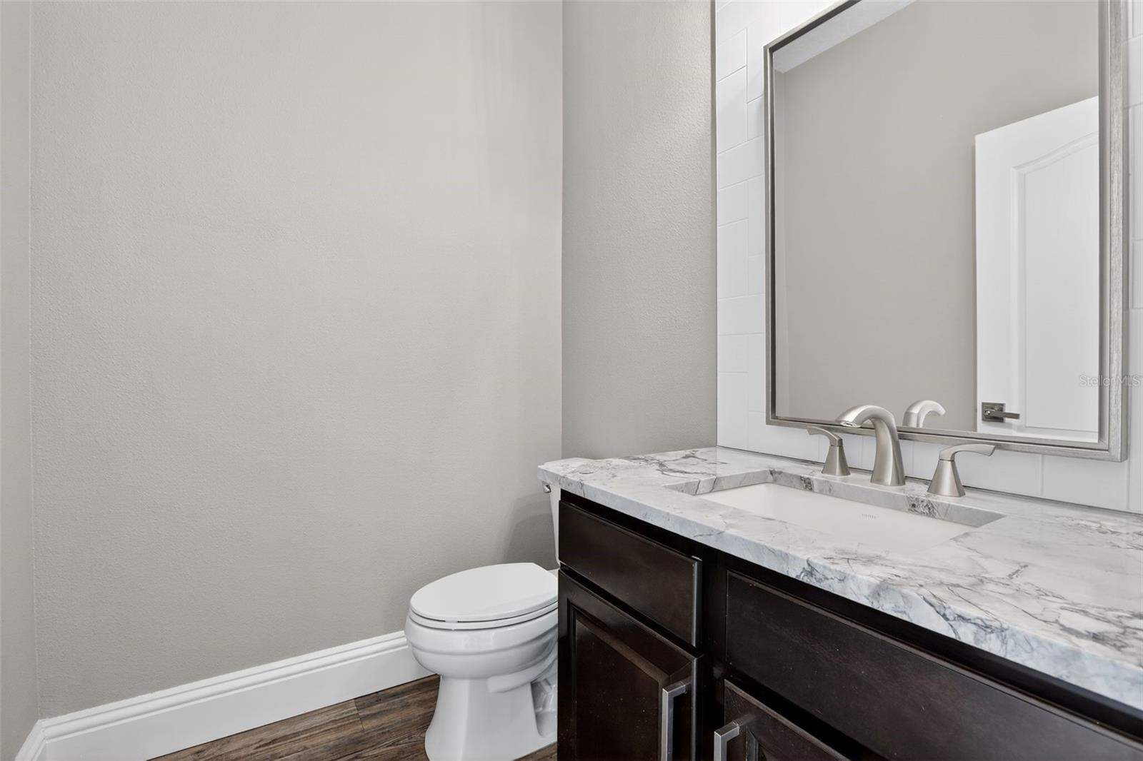 Downstairs half bath with beautiful Dolomite countertops & neutral tile backsplash