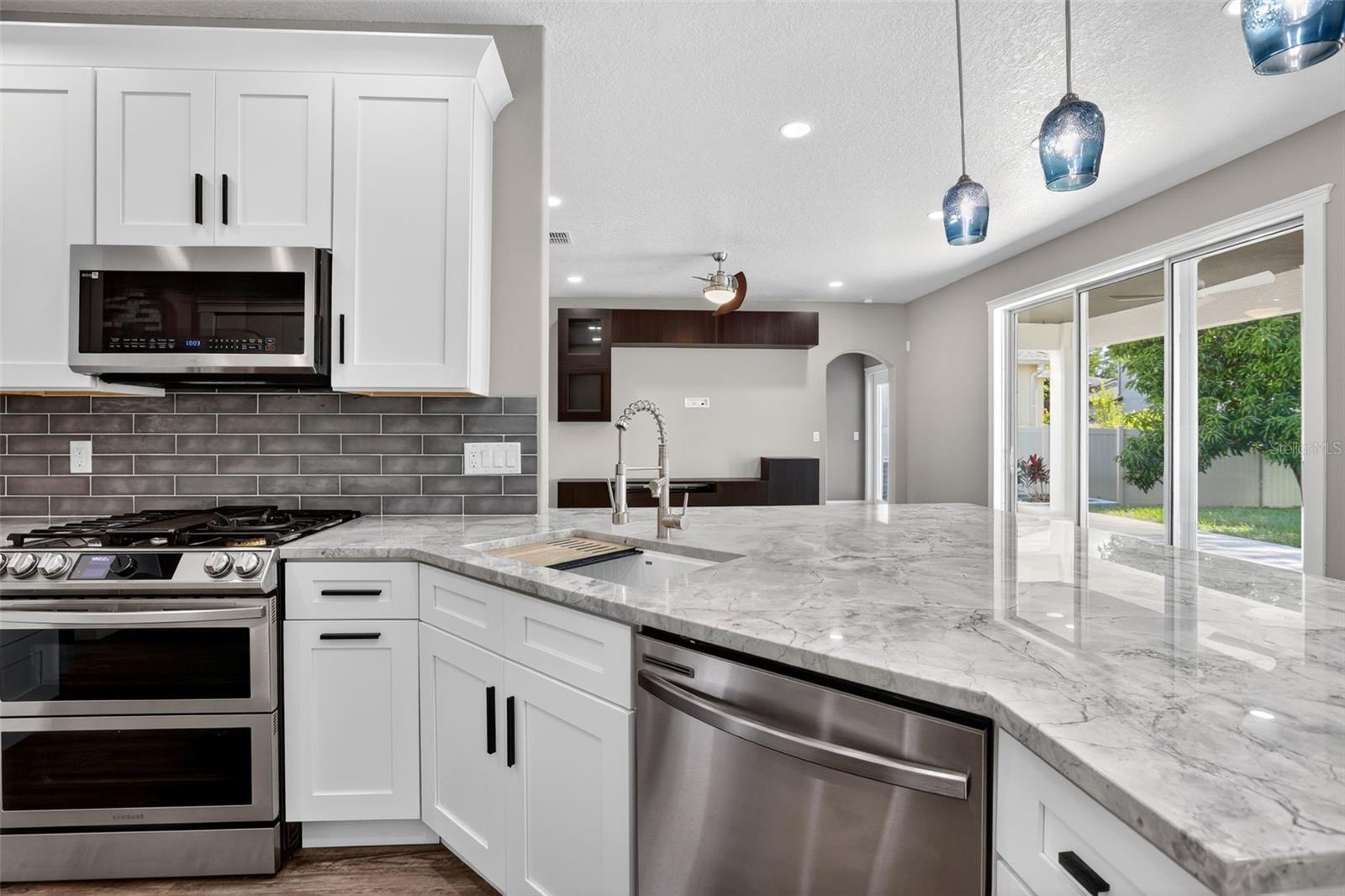 Samsung dishwasher and workstation sink. Hidden trash cabinet right of oven.
