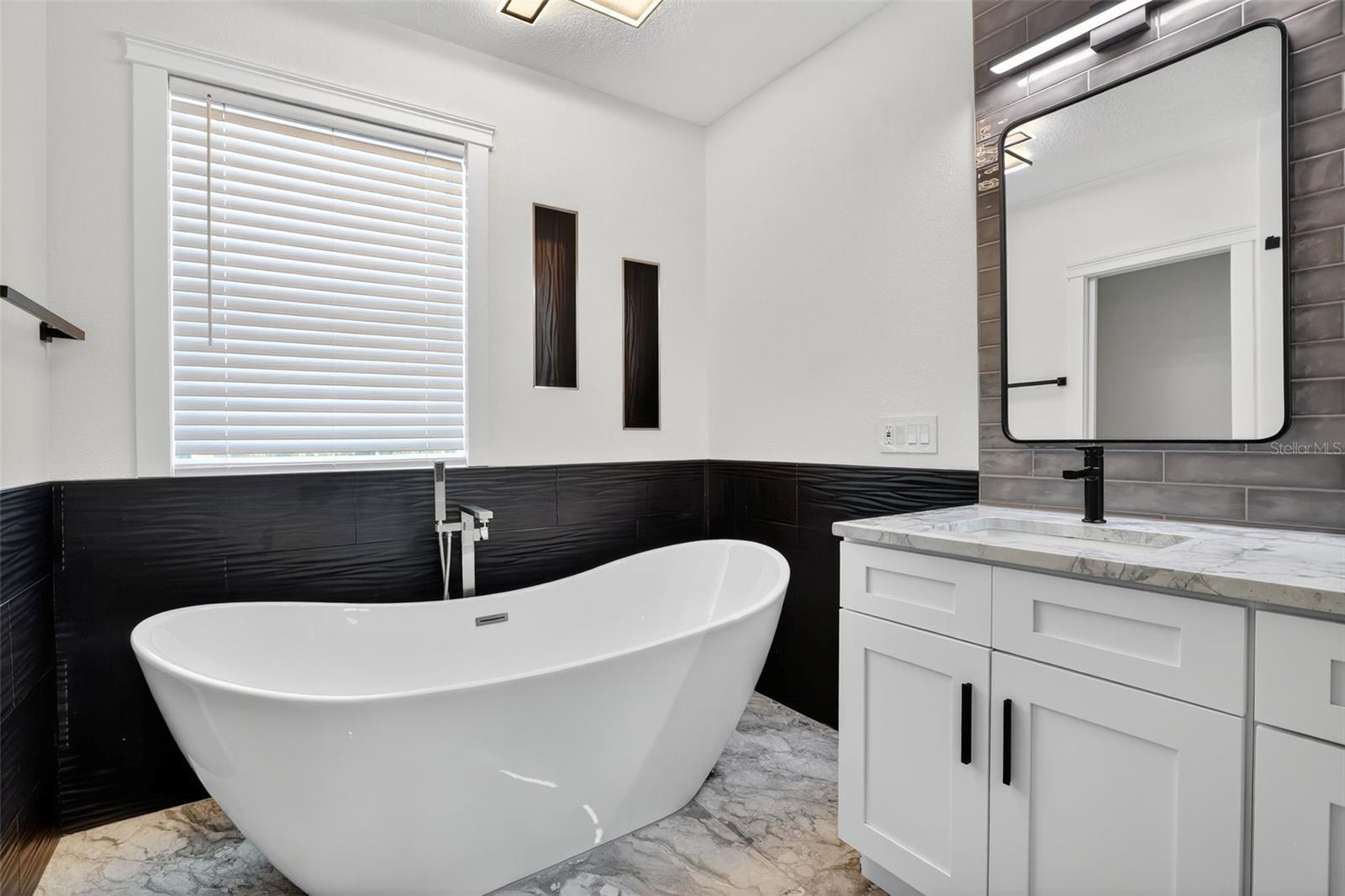 The large 71in free-standing soaking tub with detachable faucet & built-in niches creates a cozy atmosphere.