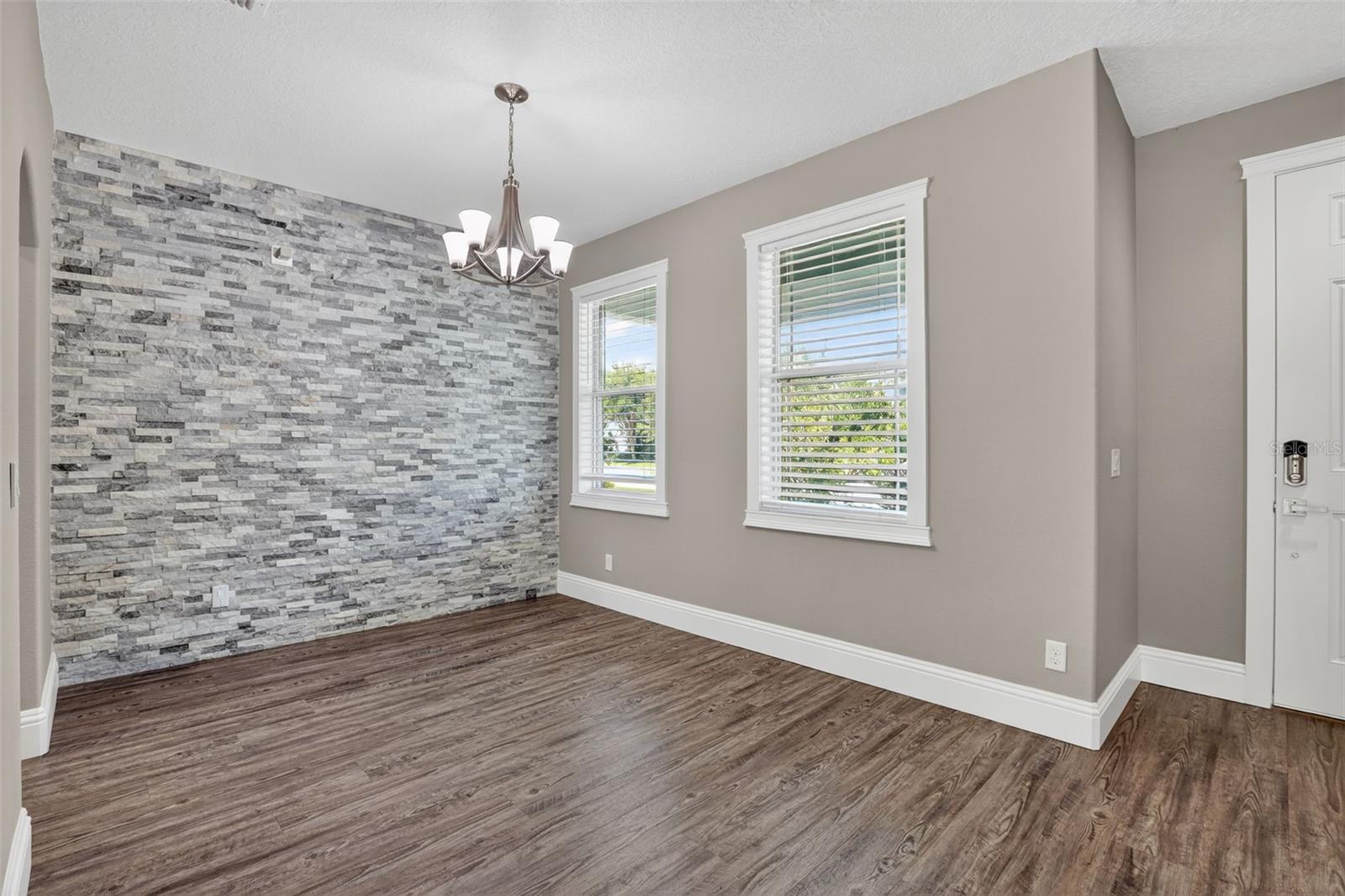 Gorgeous stone accent wall with down-lighting in dining room.