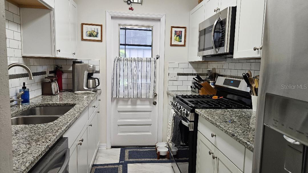 BEAUTIFUL KITCHEN WITH GRANITE COUNTERTOPS STAINLESS STEEL APPLIANCES,DOOR GOING OUT TO THE SCREENED PORCH.