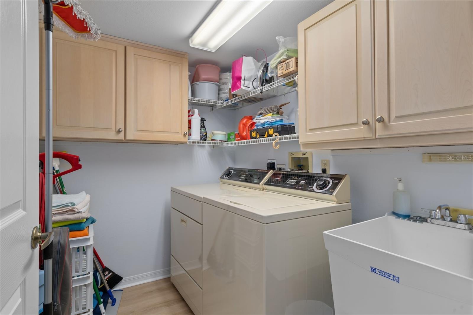 LARGE LAUNDRY ROOM WITH UTILITY SINK AND STORAGE CABINETS IN CONDO