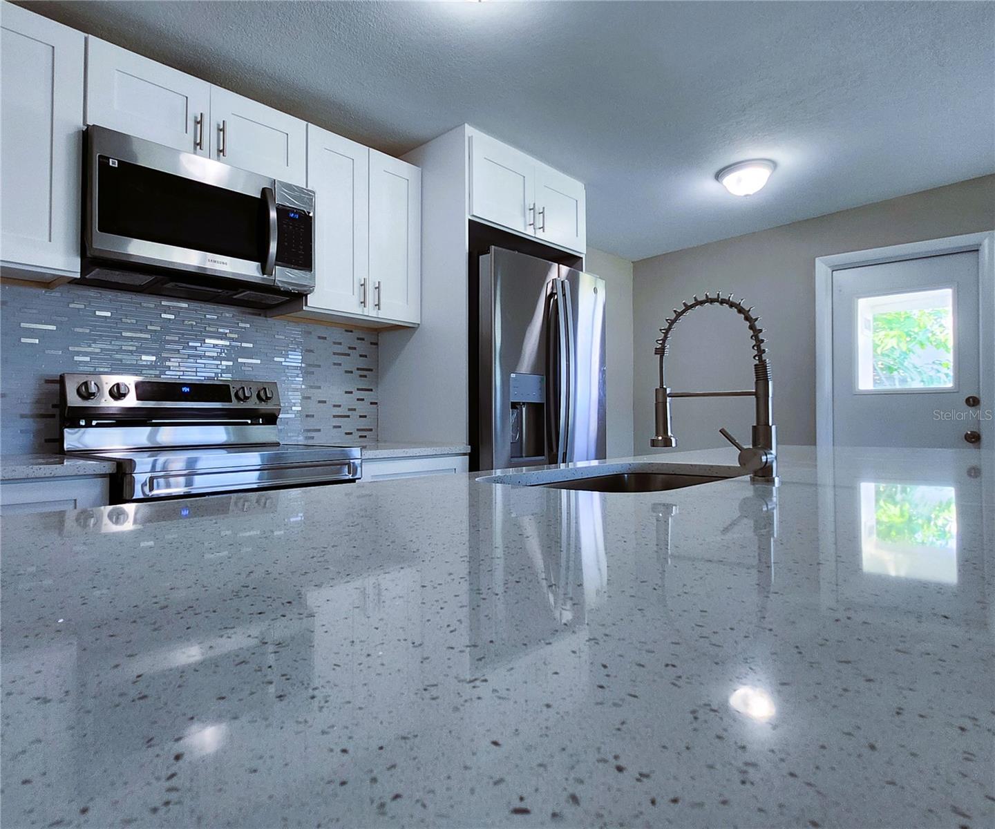 Kitchen includes granite countertops,  backsplash, new refrigerator, new stove, new microwave