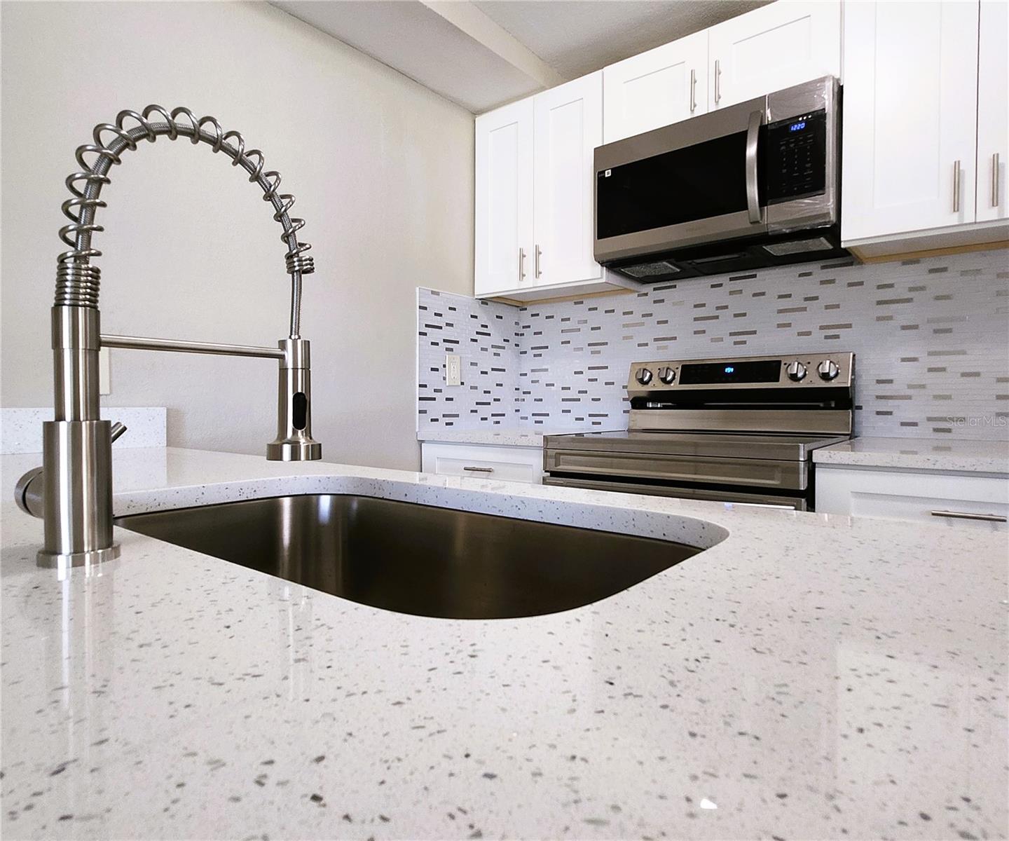 Kitchen includes granite countertops,  backsplash, new refrigerator, new stove, new microwave
