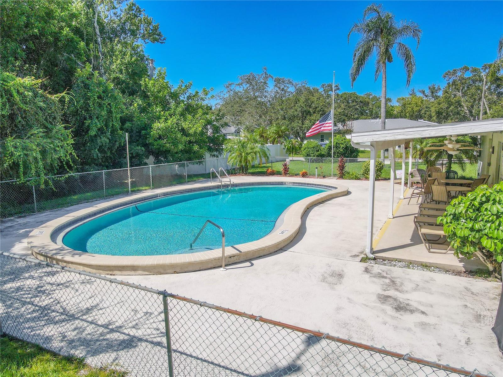 Community pool with covered seating area offers a refreshing escape just steps from the villa.