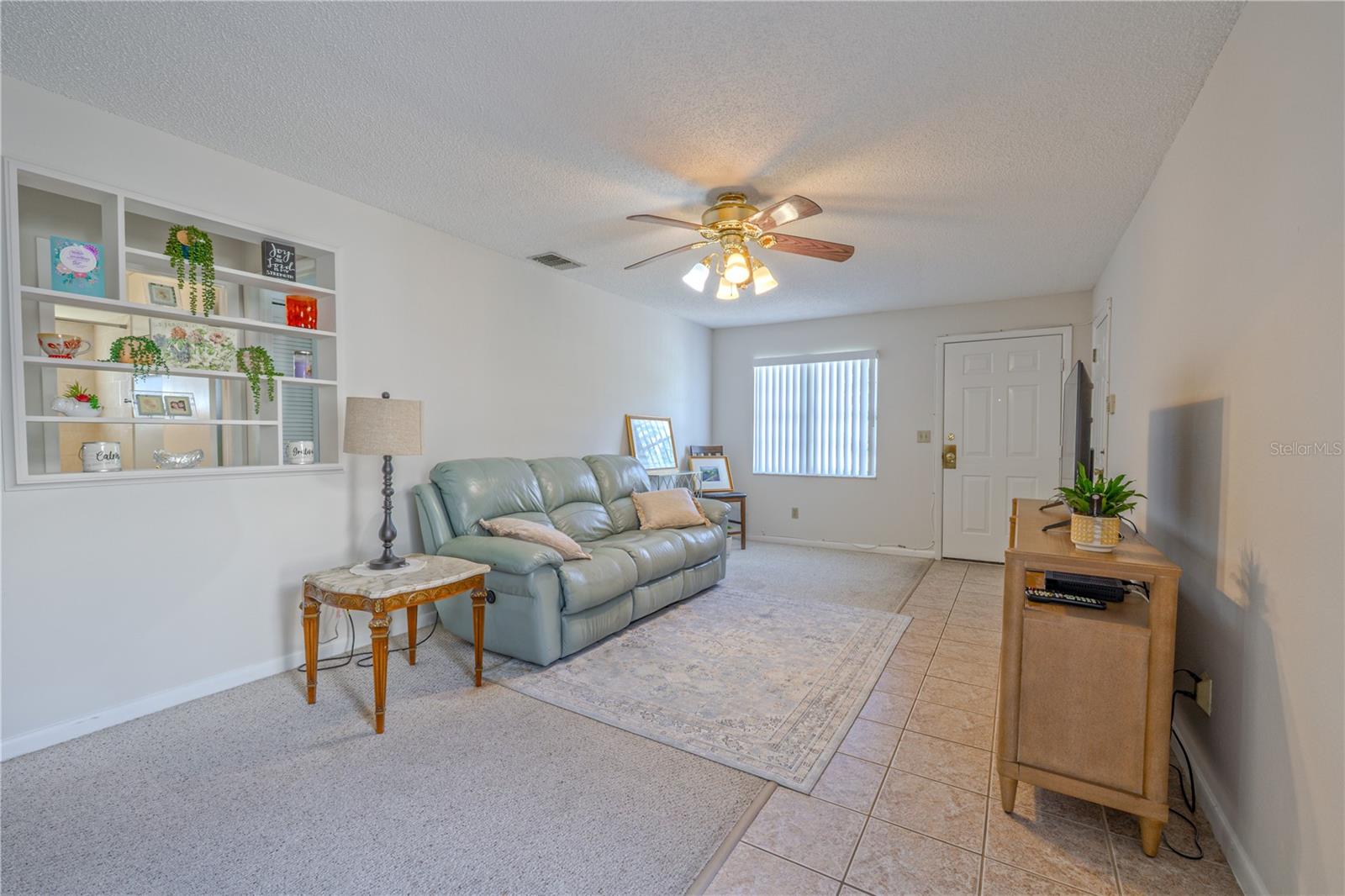 Bright living room with a ceiling fan and neutral finishes, ready to fit any style of décor.