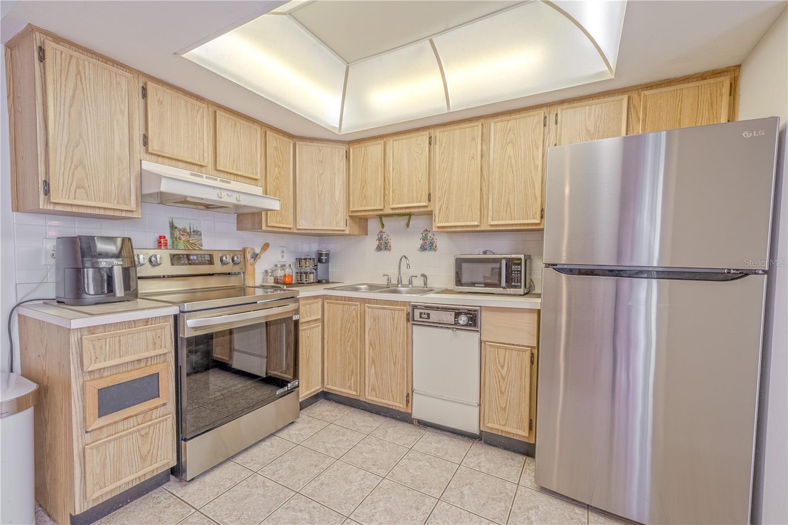 Kitchen with 2024 stainless refrigerator and 2025 range/oven, plus overhead lighting for a bright workspace.