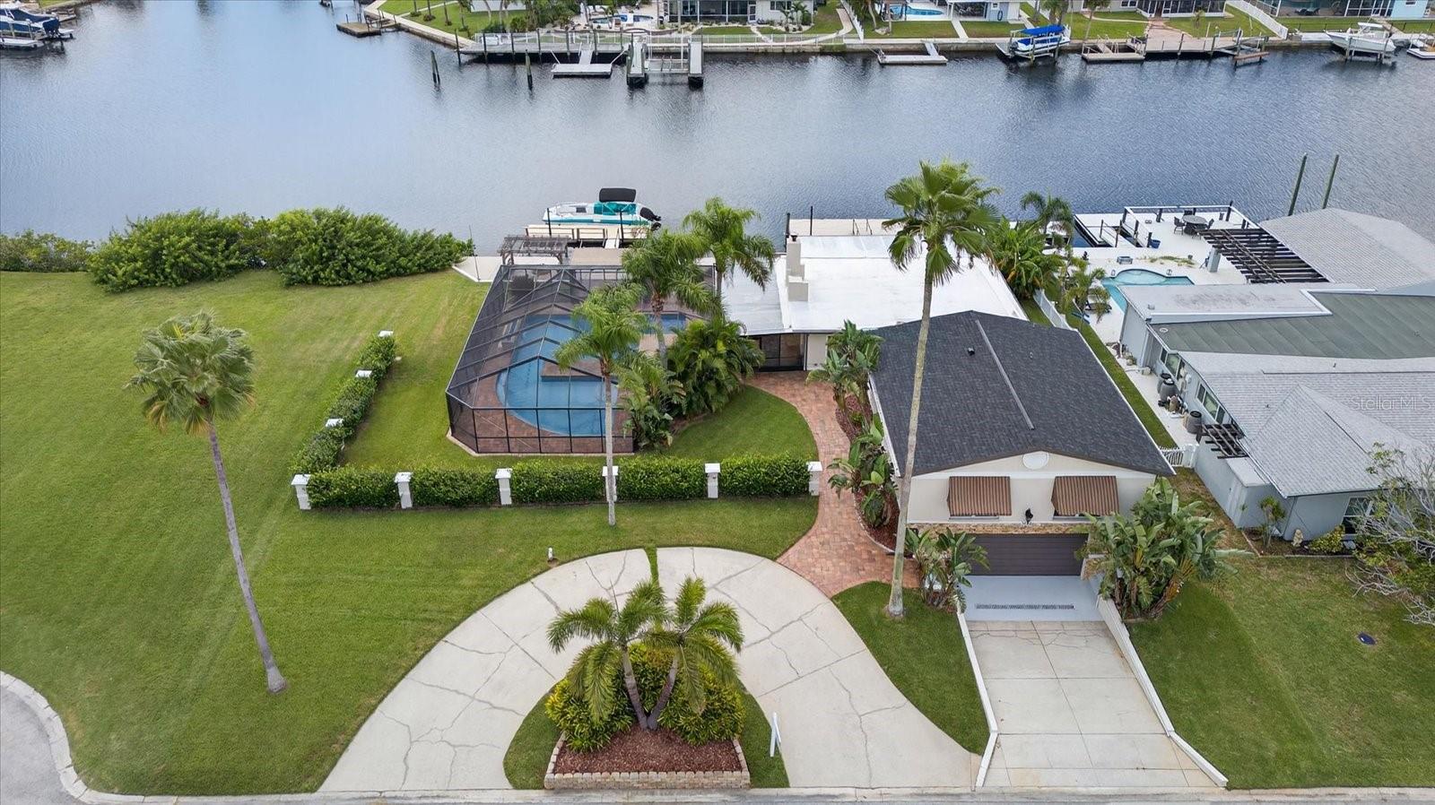 Aerial view of waterfront double lot with circle driveway and lower garage entry in cul-de-sac