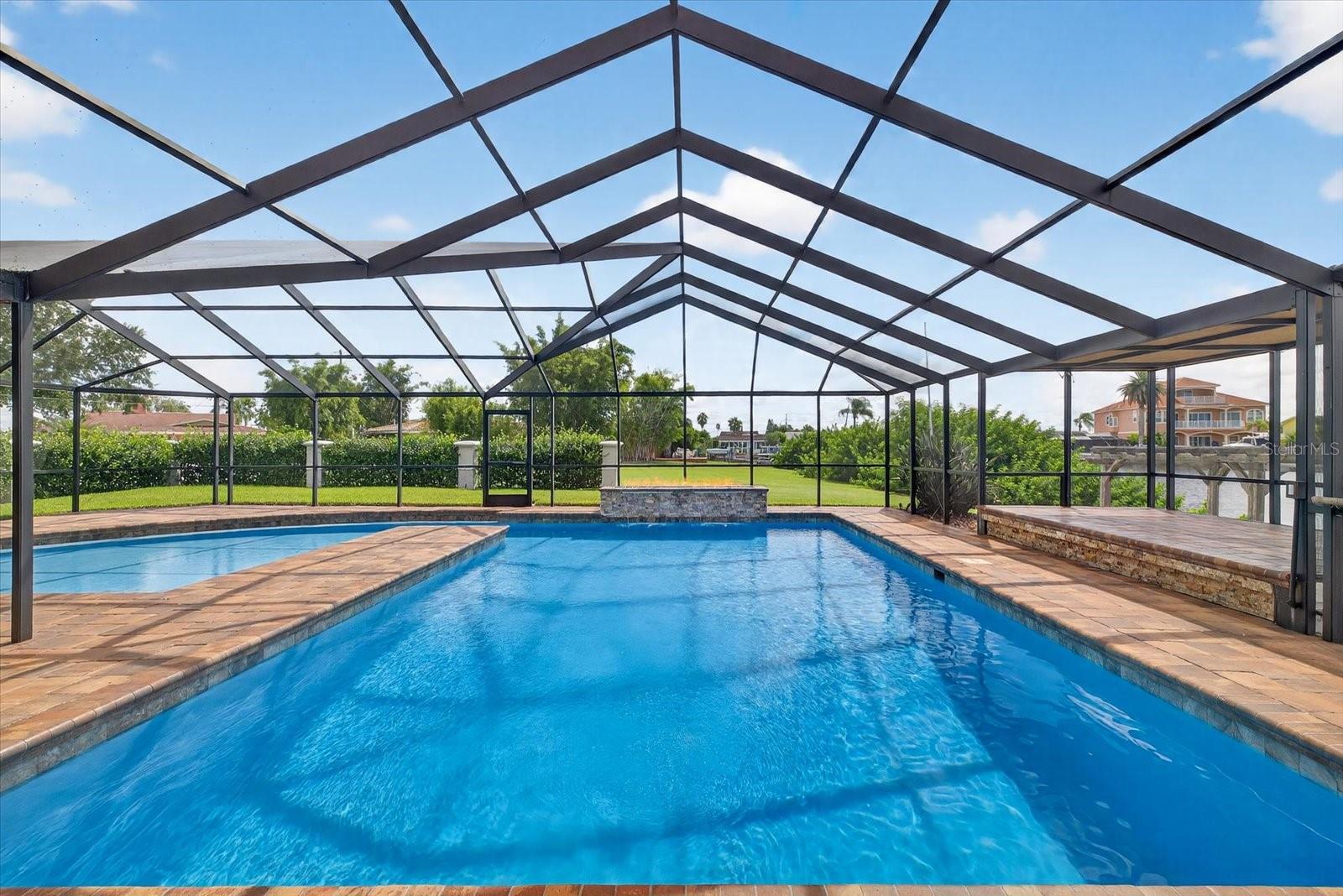 Saltwater pool dual swim/conversation areas with gas flame feature and spillover waterfalls.
