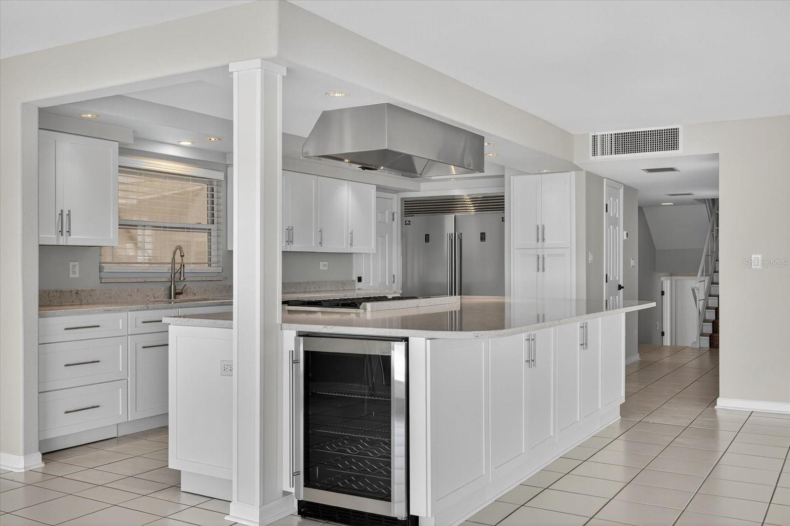 View of kitchen with mini beverage unit in massive island with FORNO gas range/oven