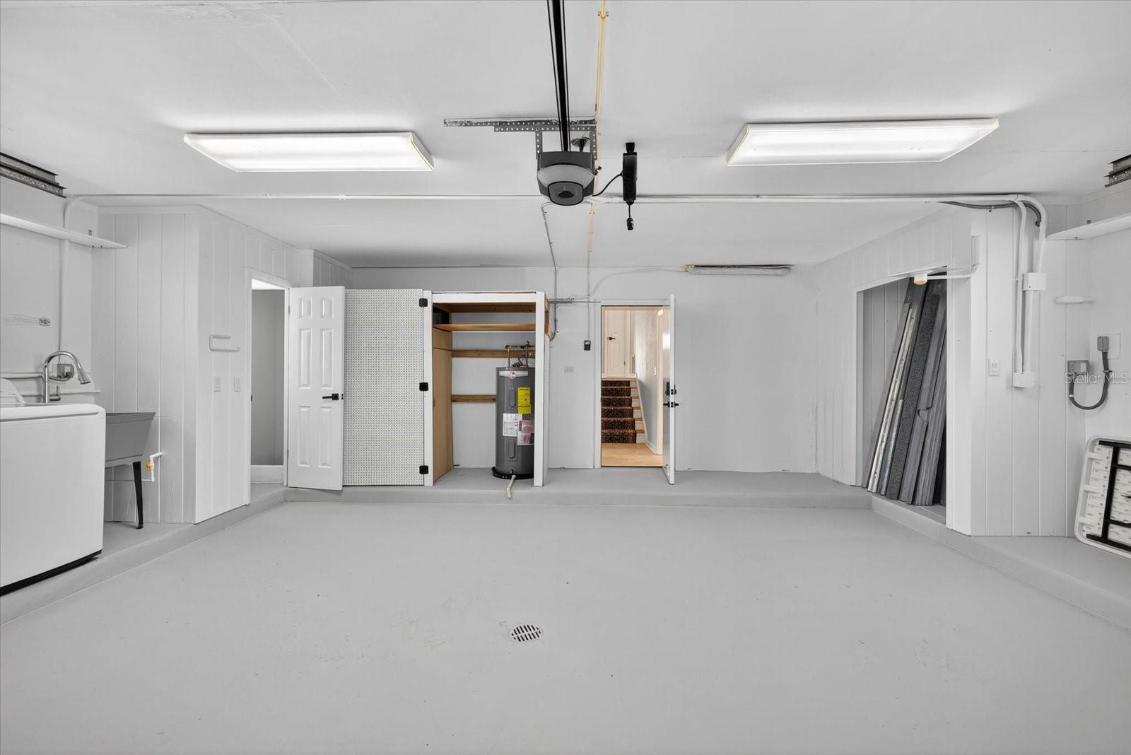 Garage with drain showing hurrican shutter storage, laundry area and water heater closet.