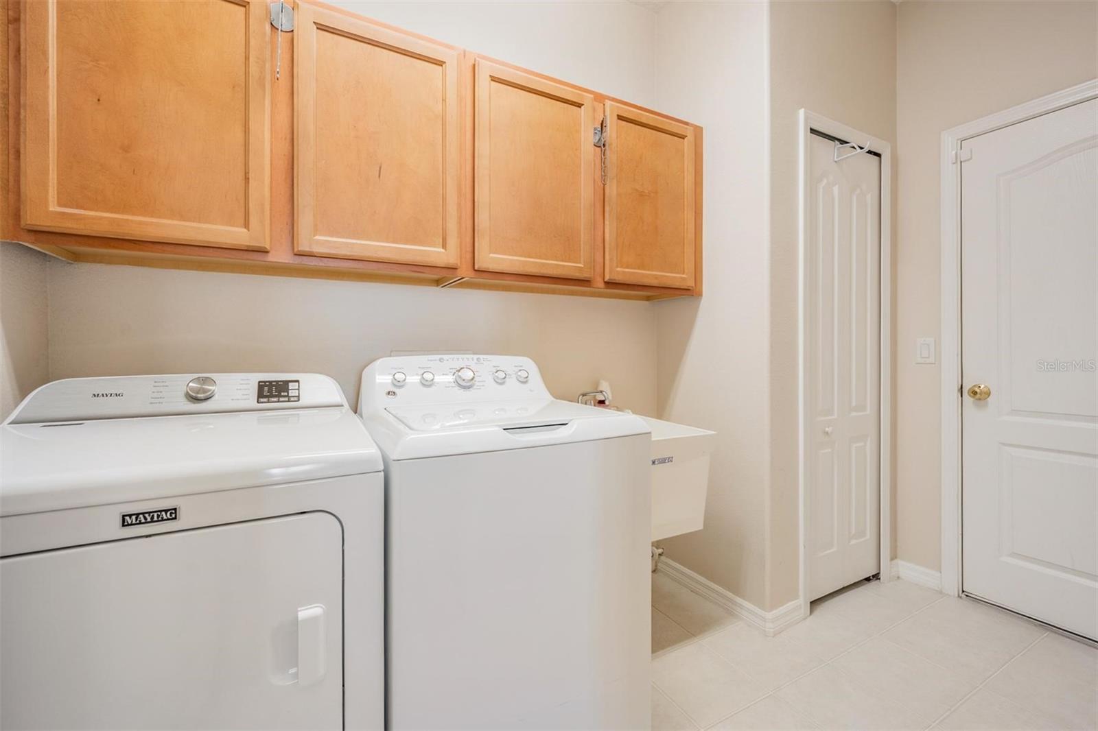Walk-in laundry room with built-in cabinets and utility sink