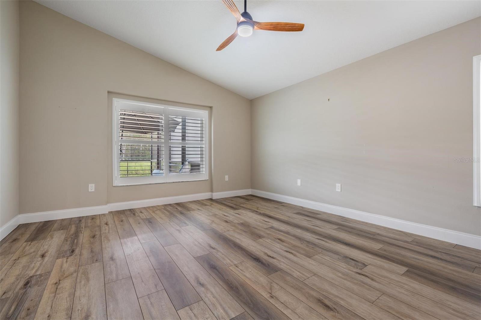 Primary bedroom with a vaulted ceiling and LVP flooring