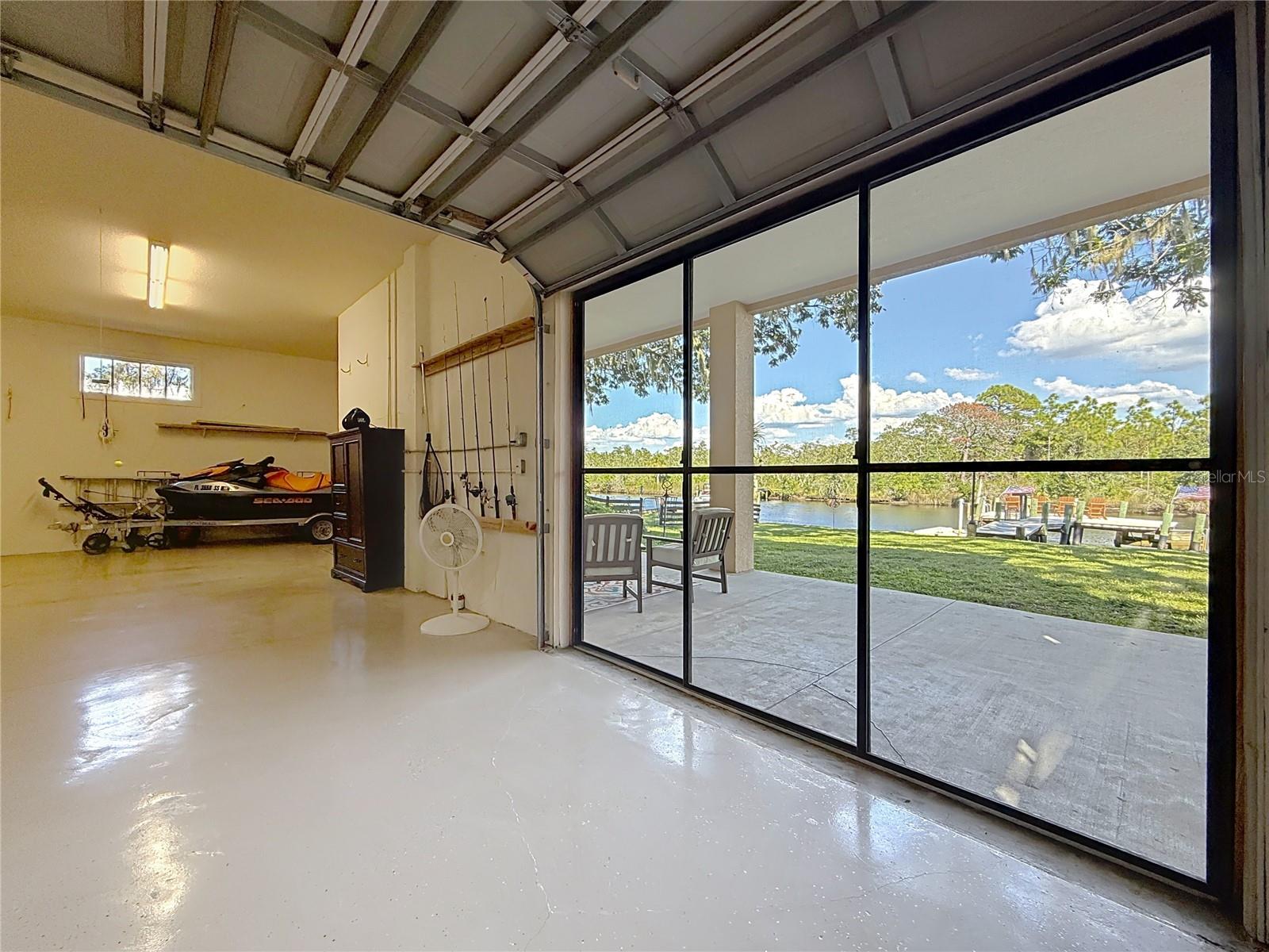 Rear Garage Stall with overhead door and retractable screen - Rear Patio - Green Space with Dock & River beyond