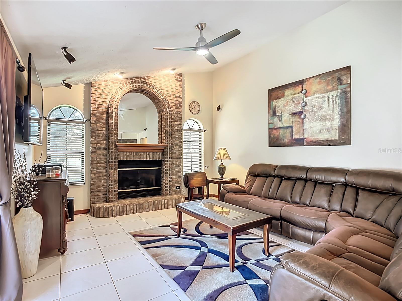 Awesome living room with brick fireplace,high ceilings , full of sunshine .