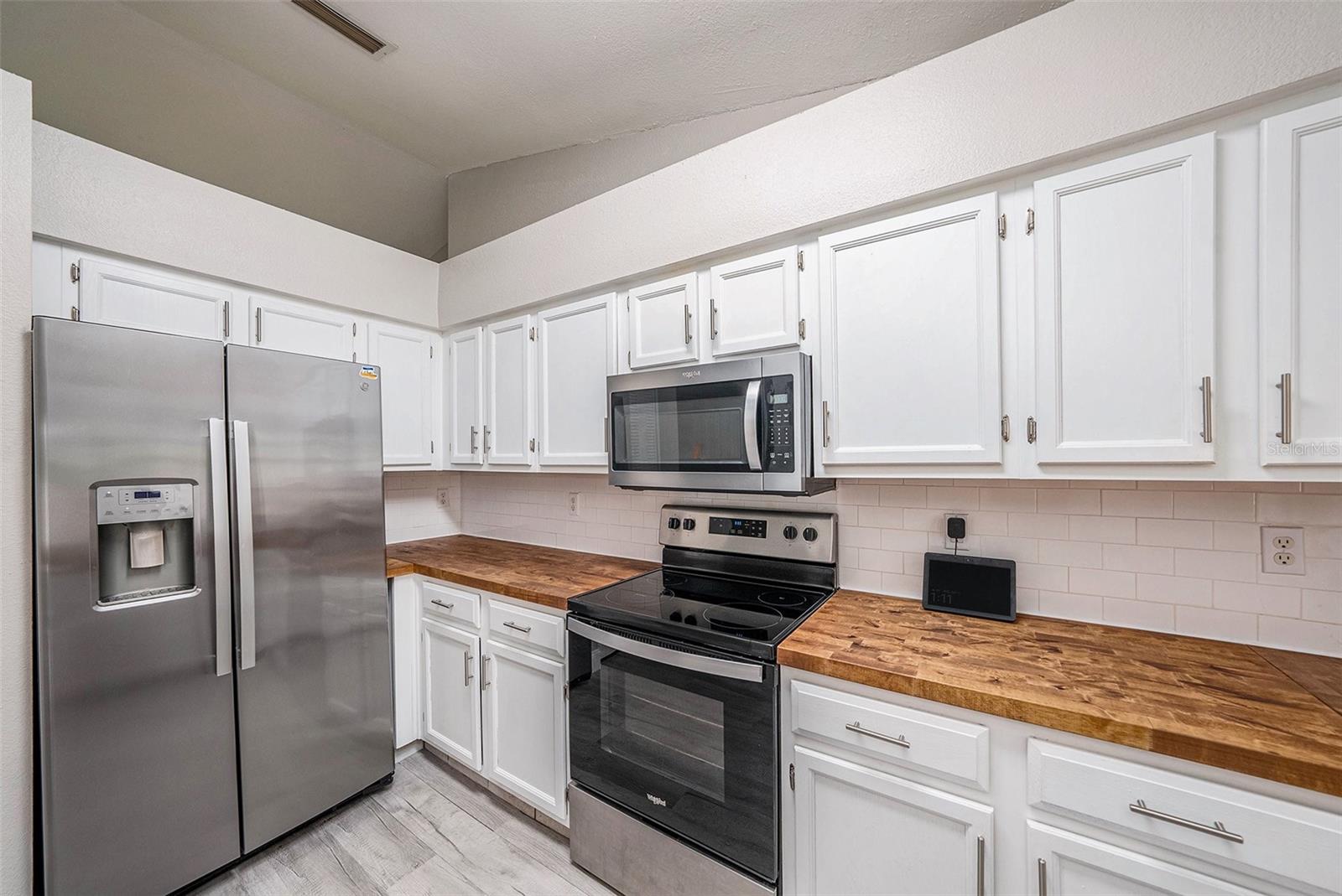 Beautiful kitchen with butcher block countertops, wooden cabinetry, stainless steel appliances, and pantry.