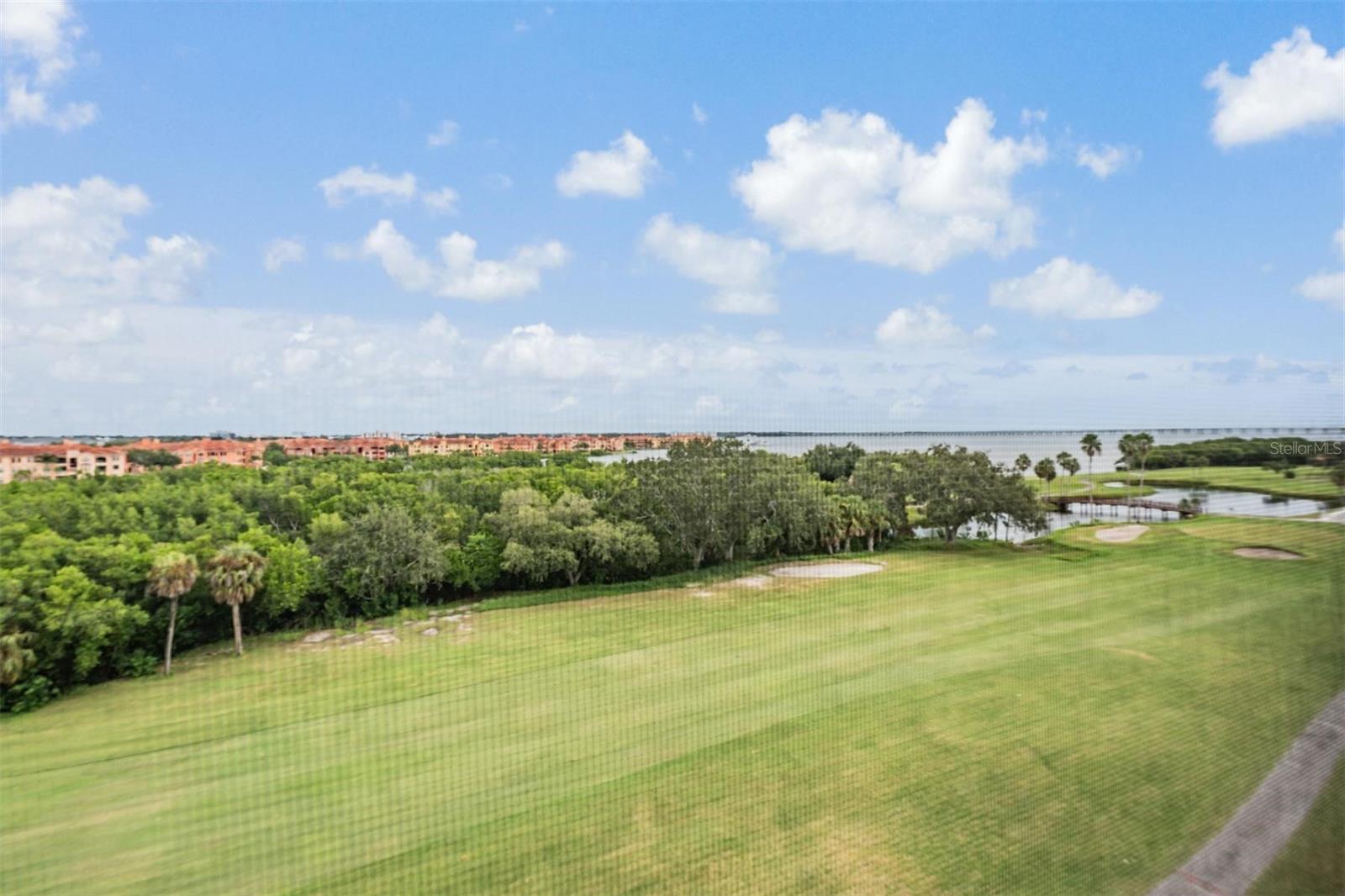View of golf course and bay with bridge