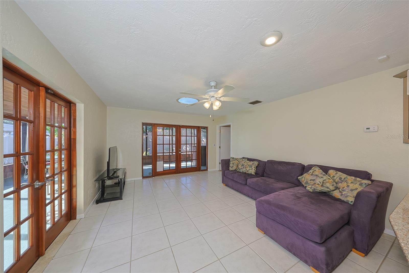 Family room with door to primary bedroom, back right. Beautiful wood doors to the wrap-around screened porch.