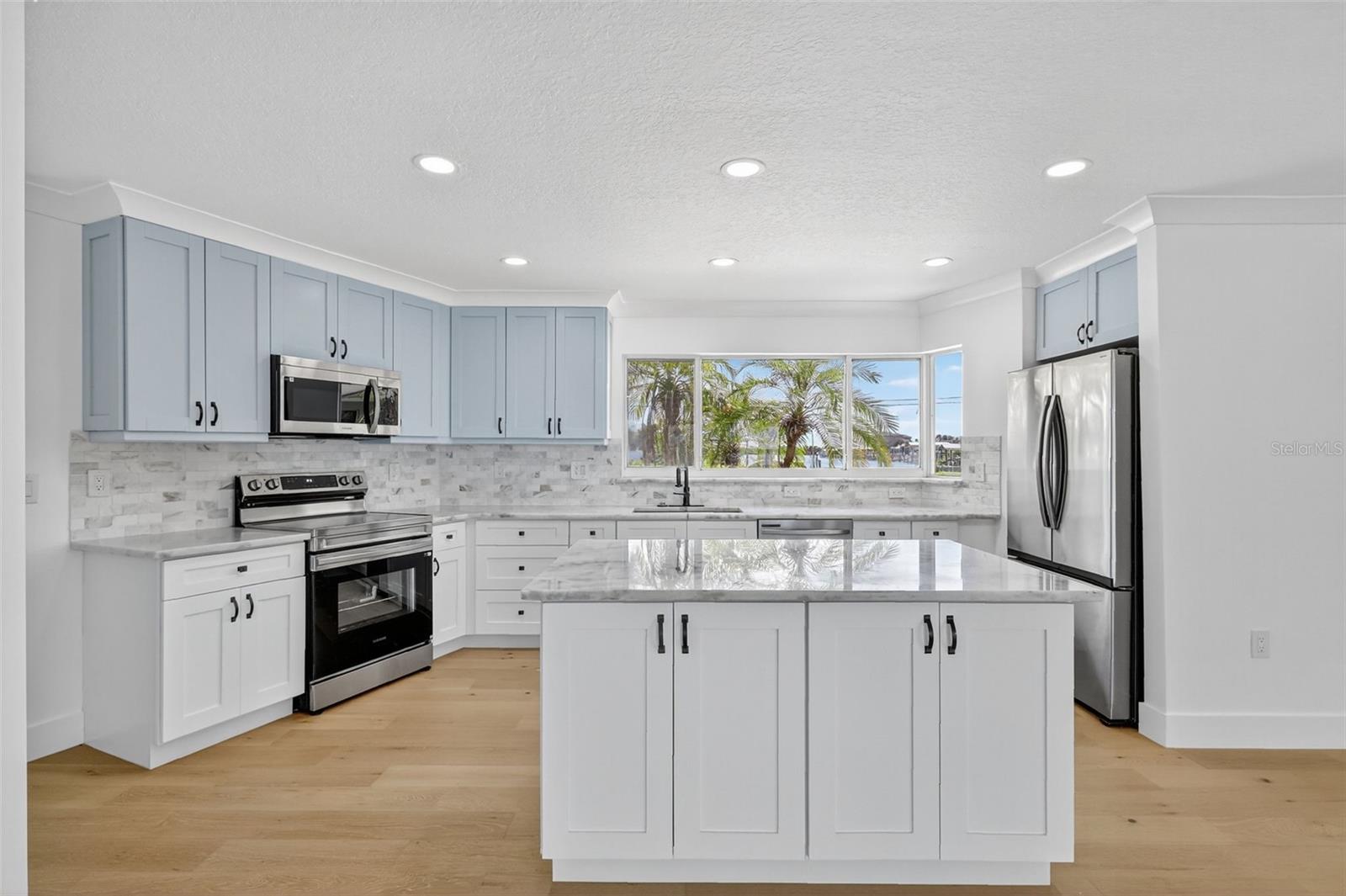 The kitchen has two toned cabinets, New Samsung Stainless steel applicance , quartz counters, an island with extra storage and an abundance of light.