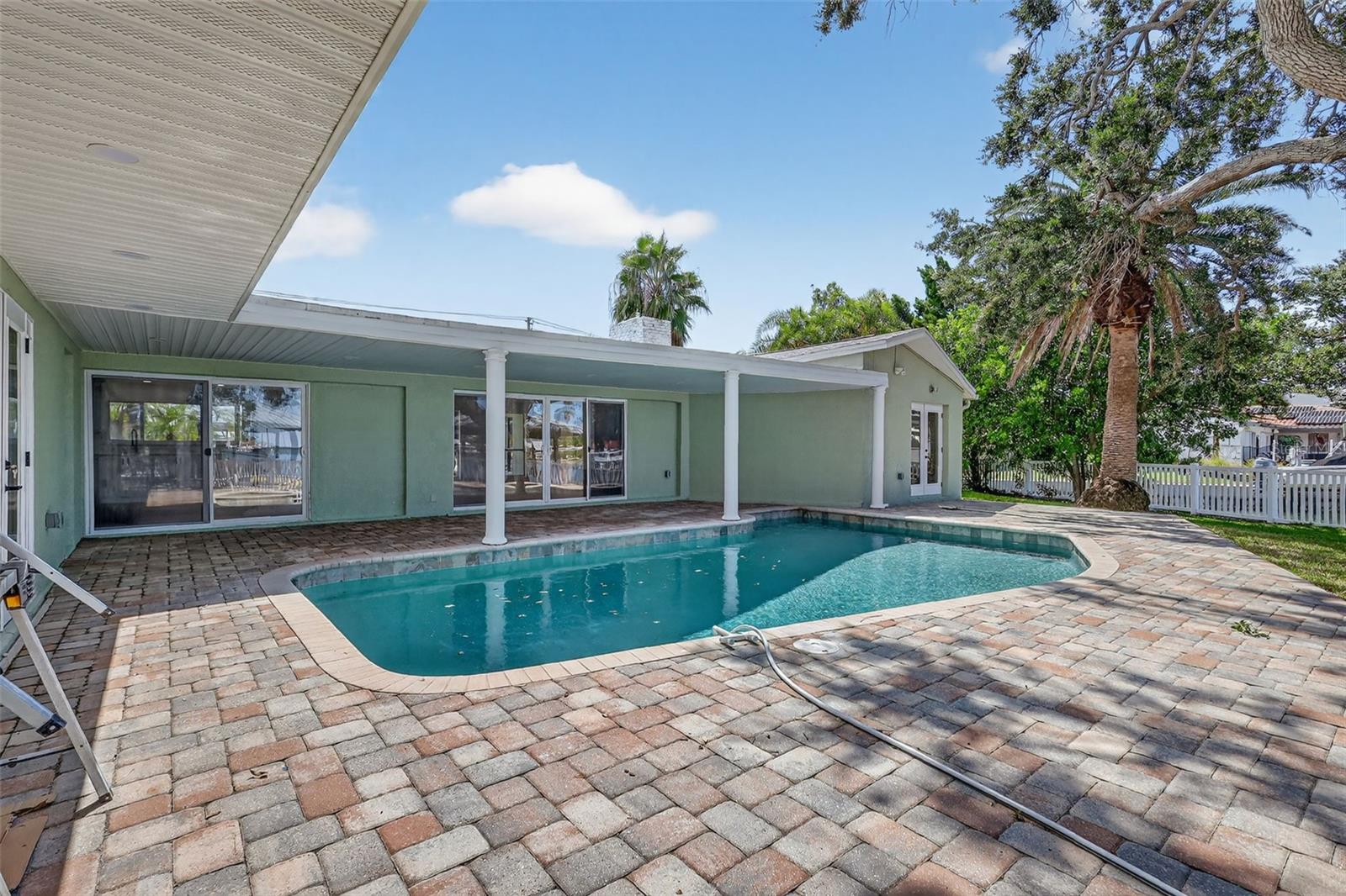 The Home has a large inviting pool, with pavered patio with plenty of space for outdoor living and dining