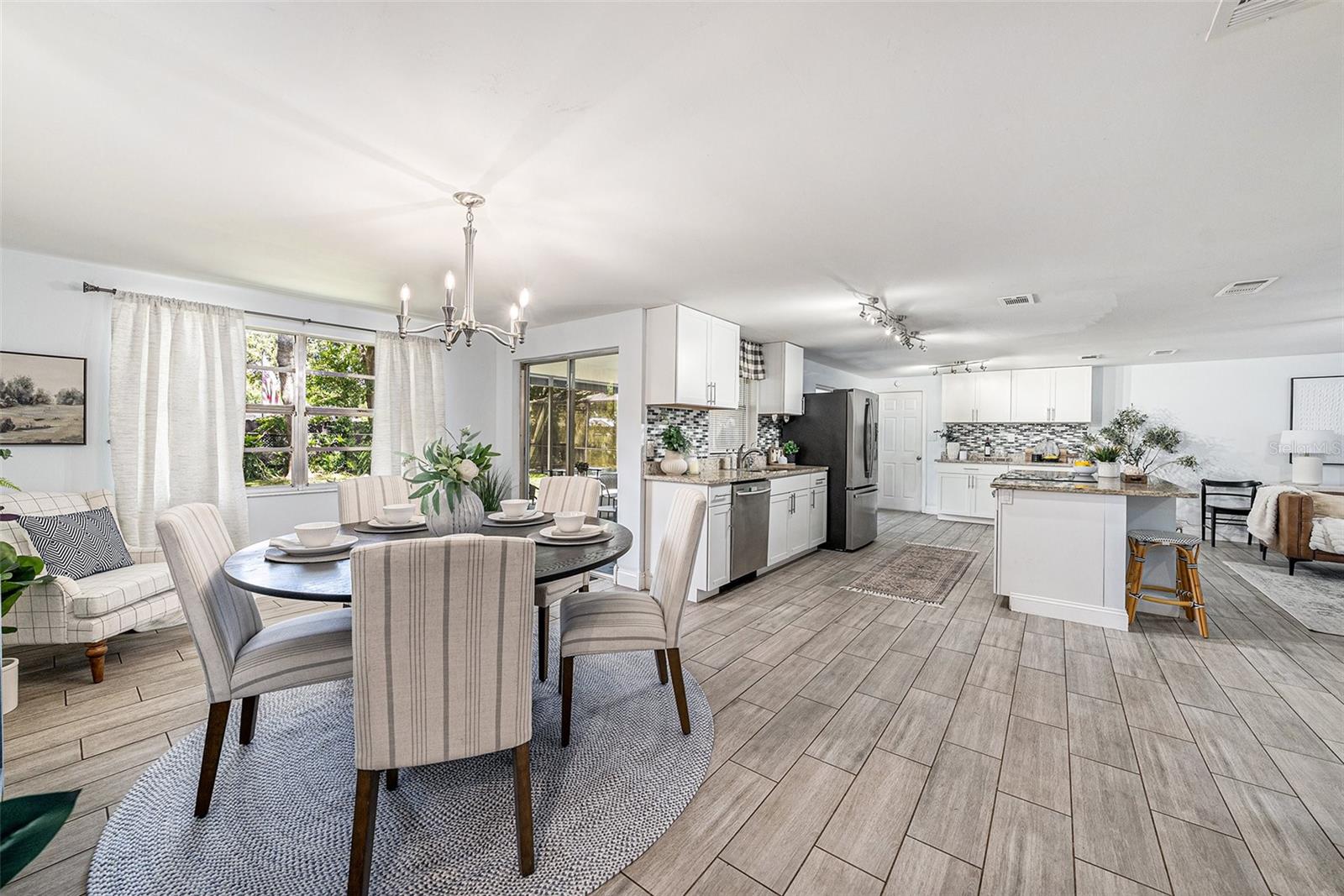 A true great room with plenty of options for furniture placement and enjoyment of a centerpoint kitchen with stainless steel appliances, entertainment island with cooktop, and two double slider doors that open to the screened pool lanai