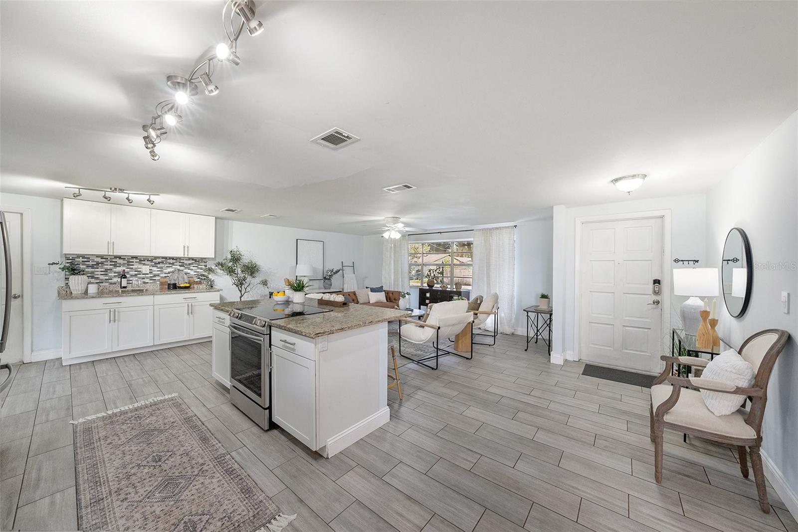 Great Room, kitchen in the center with dining, foyer, living room, and entertainment built in cabinets/counter.