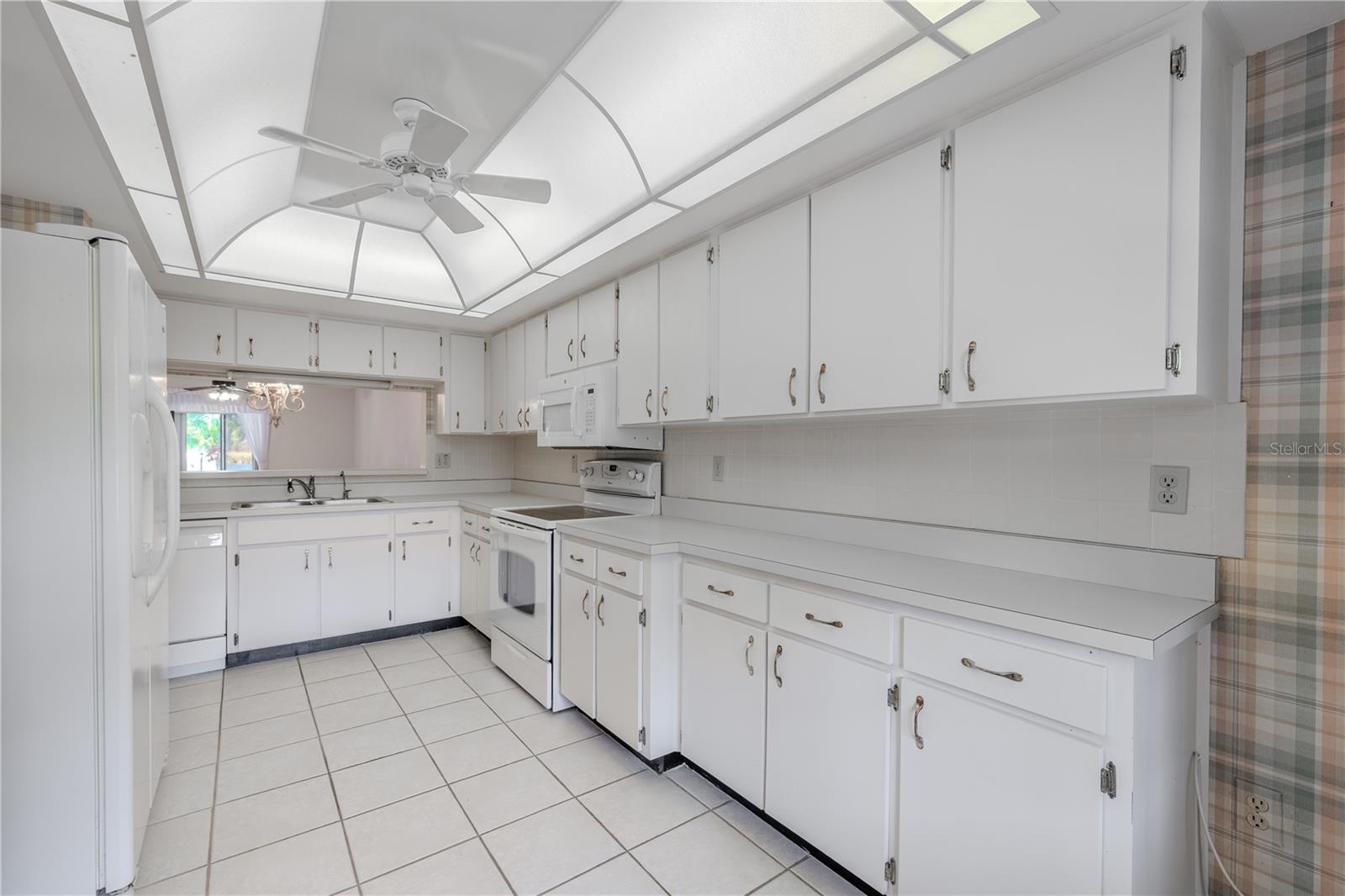 Galley-style kitchen with ample cabinetry and a breakfast bar opening to the dining room.