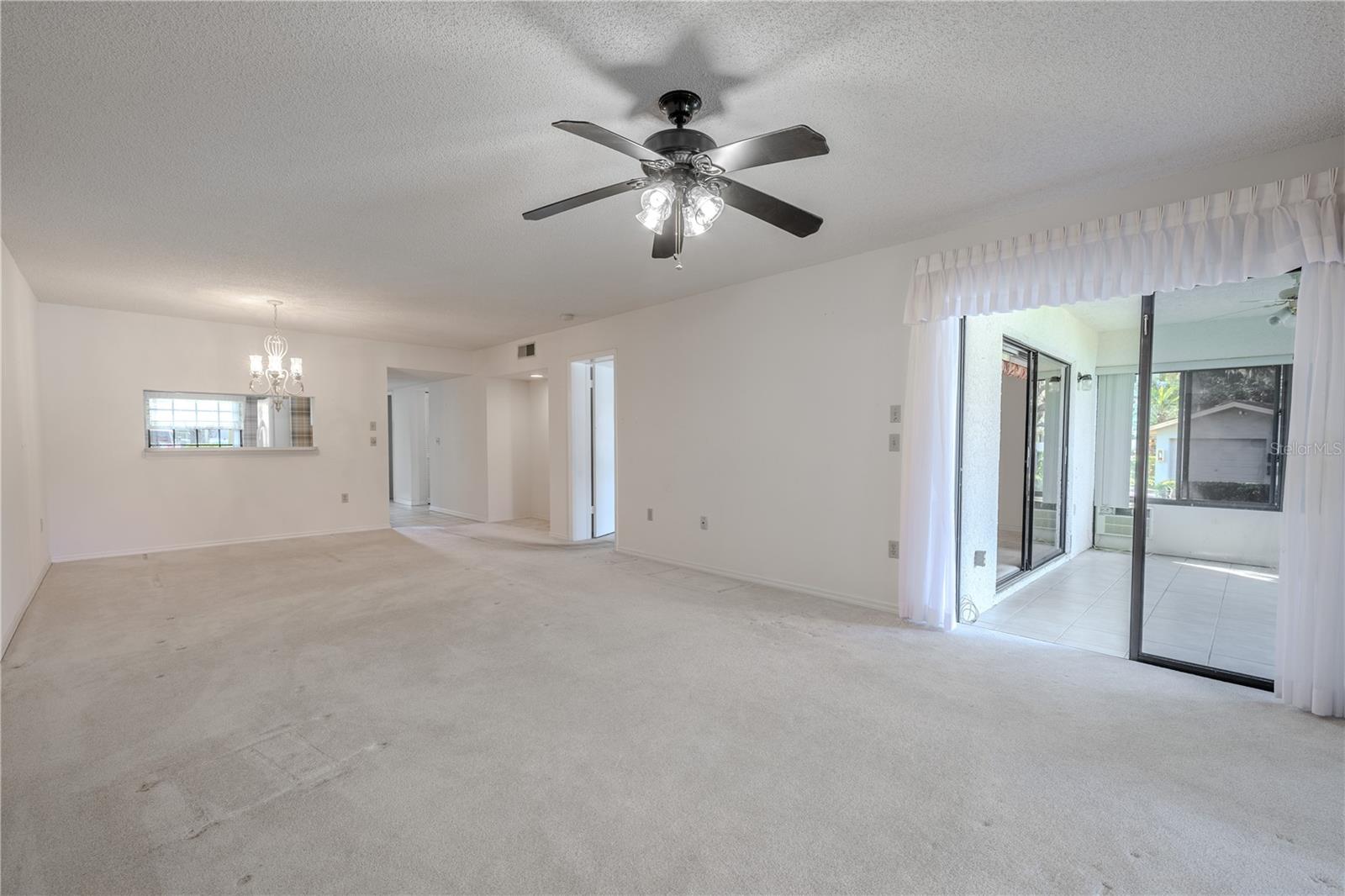 Comfortable living room anchored by a ceiling fan and sliding glass doors to the lanai.