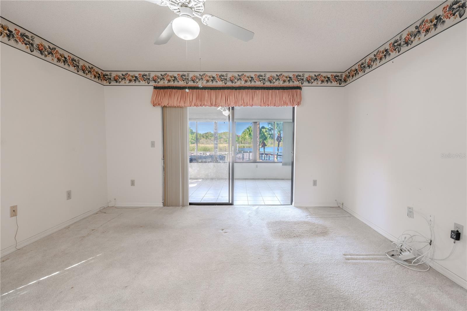 Spacious primary bedroom with ceiling fan, natural light, and lanai access.